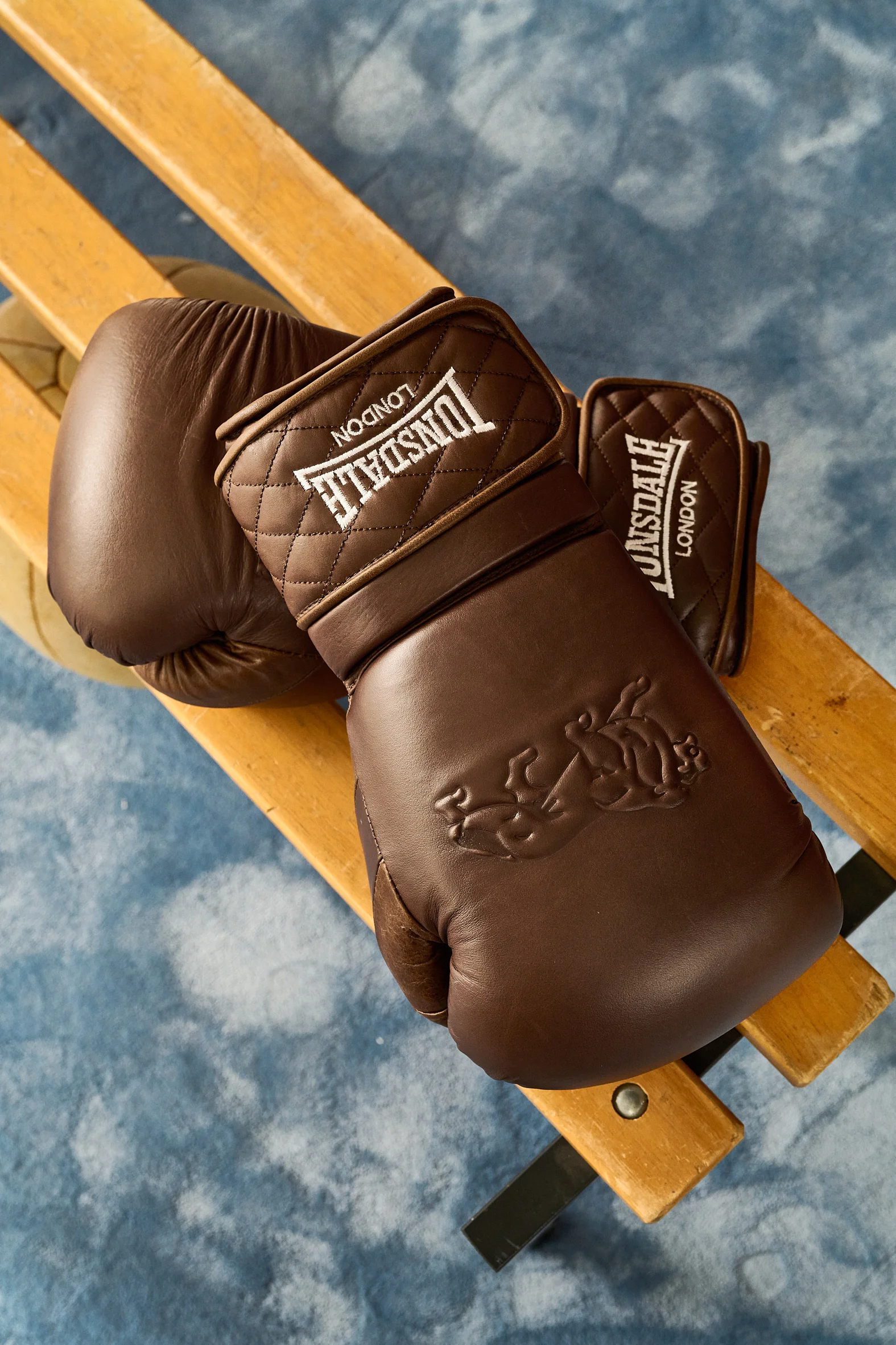 Brown Lonsdale boxing gloves on a wooden bench