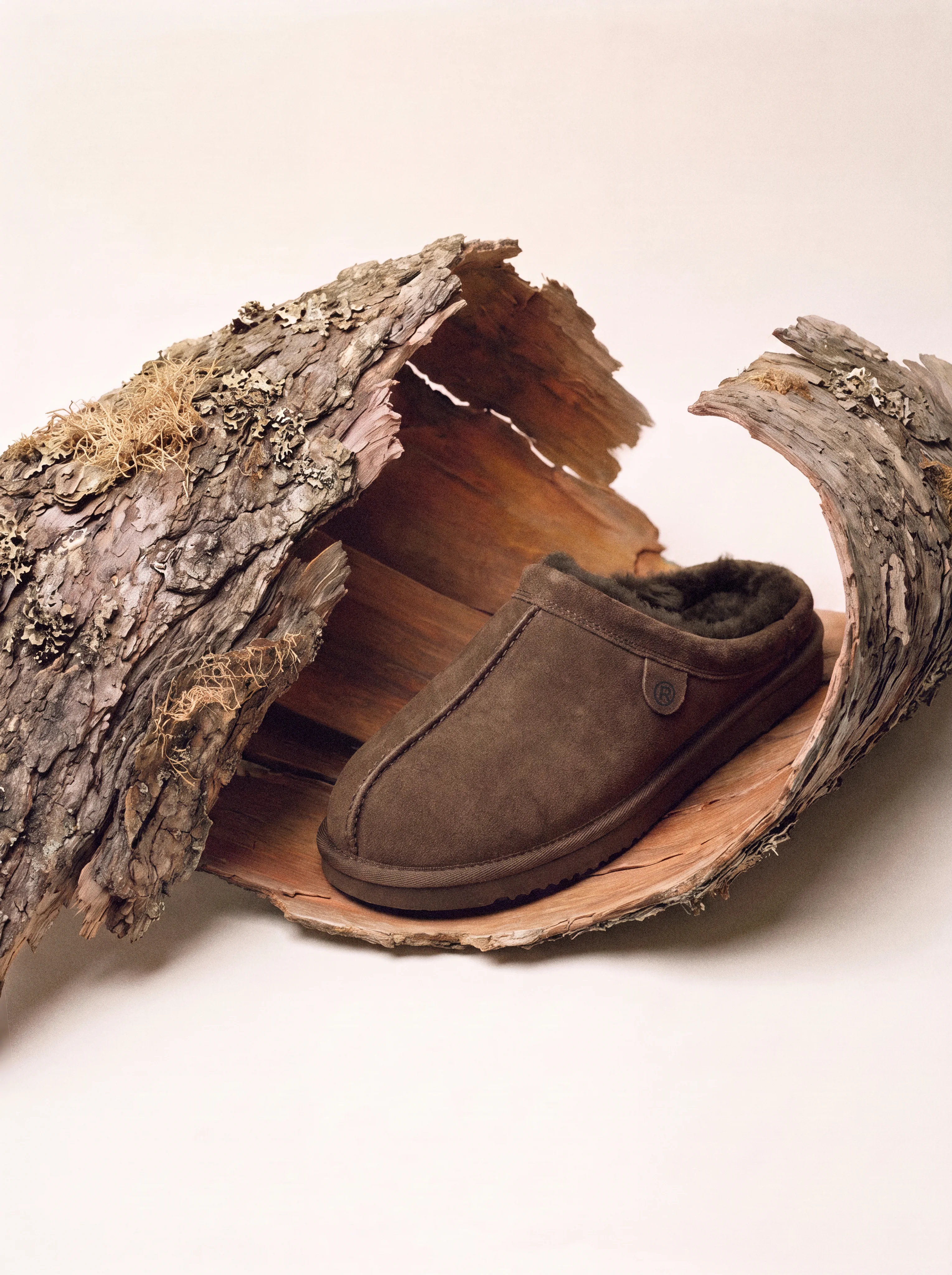 Suede slipper with shearling lining inside a piece of tree bark