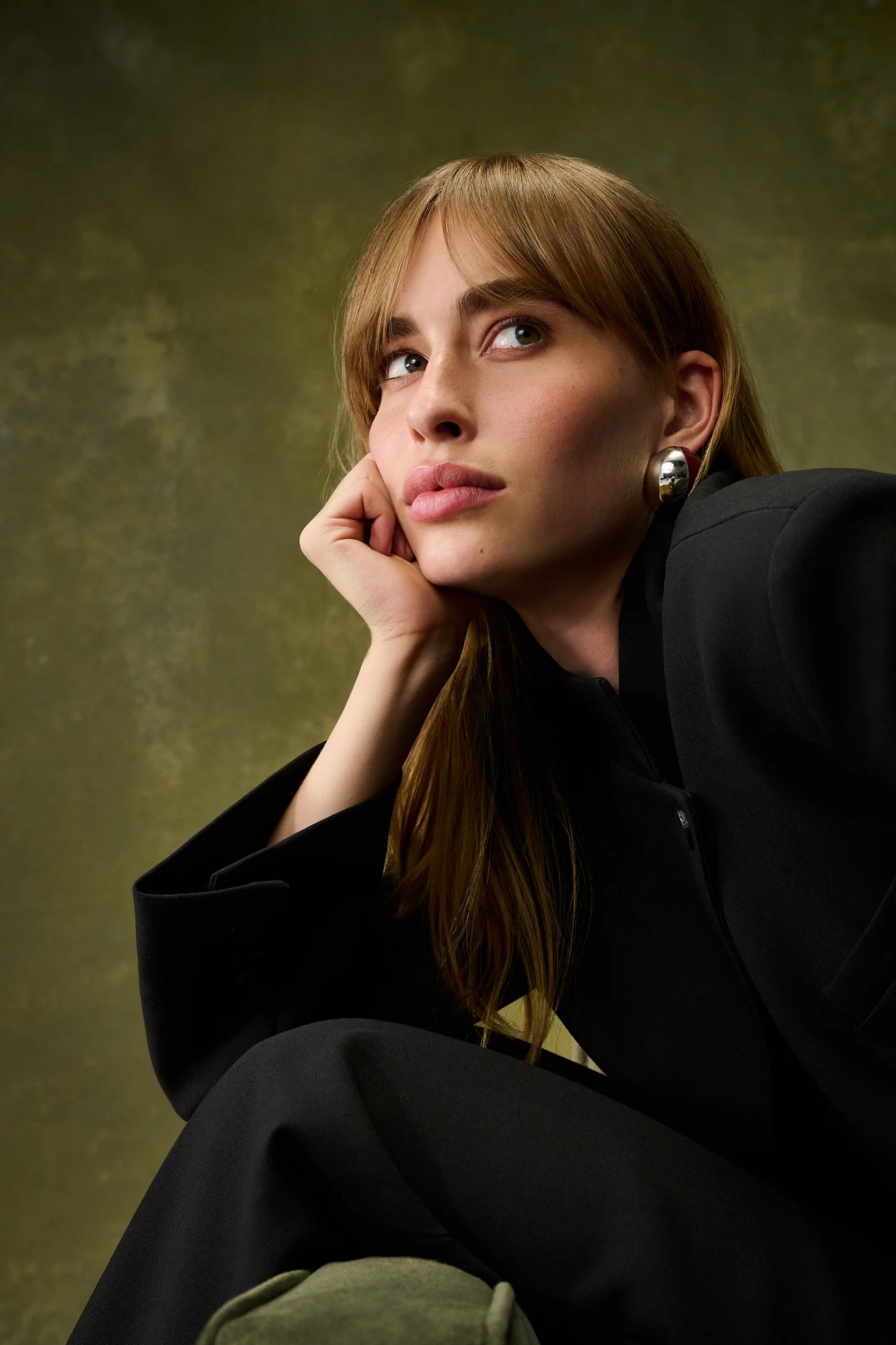 Portrait of the model in a black blazer, her chin resting on her hand