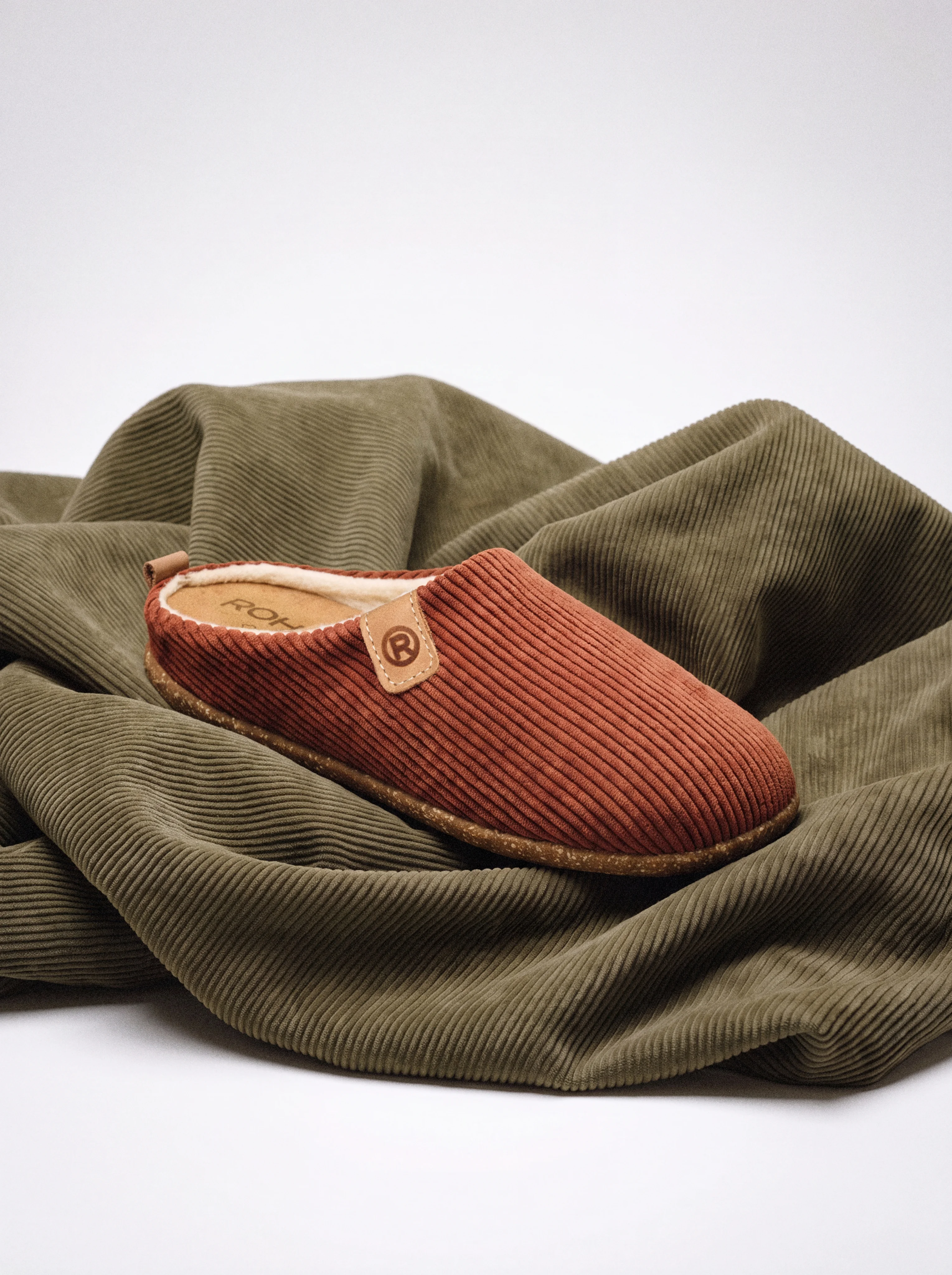 Corduroy slipper on folded green corduroy fabric