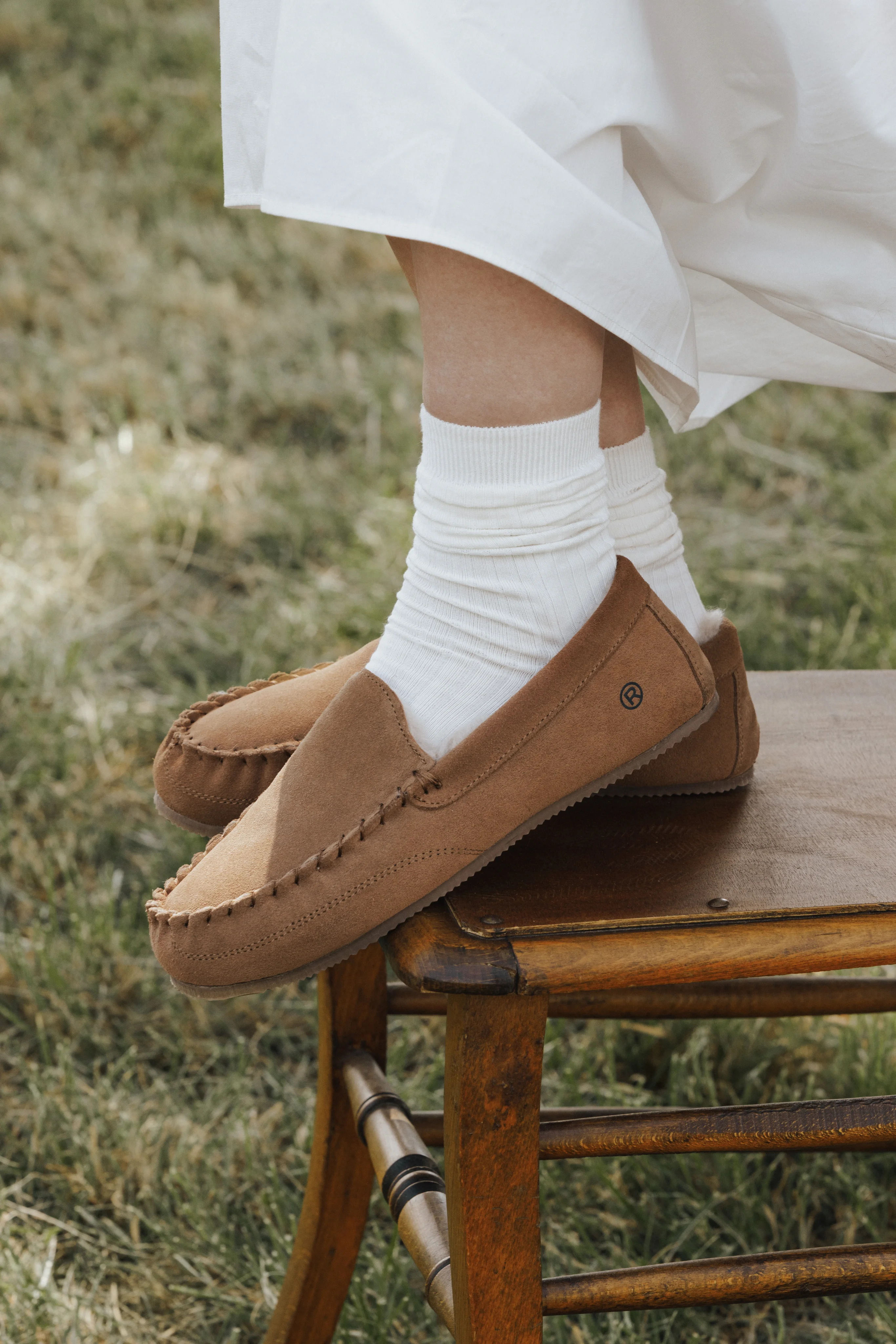 Suede moccasins and white socks on a wooden chair