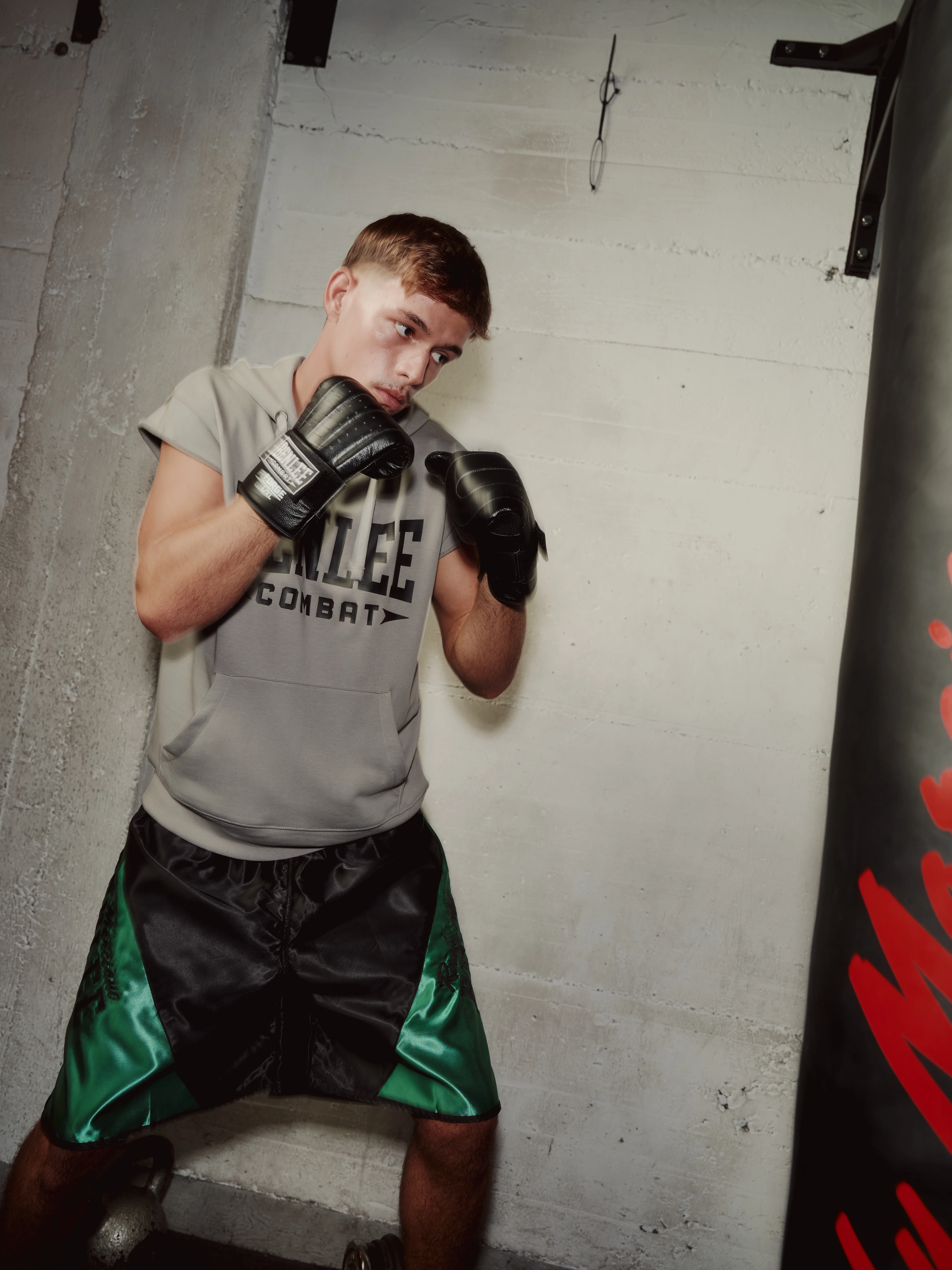 Young boxer in guard against a concrete wall