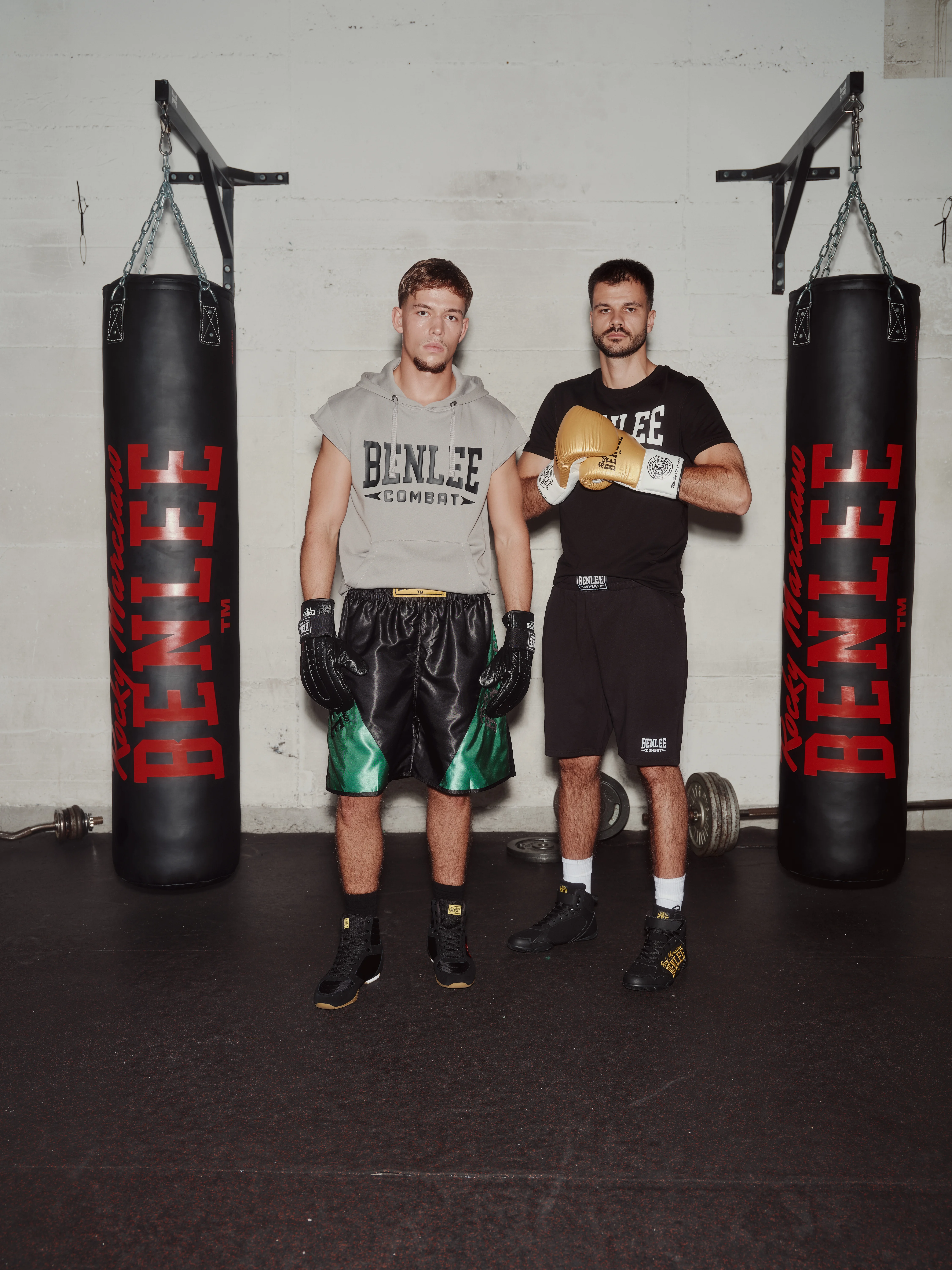 Boxer and coach posing between heavy bags