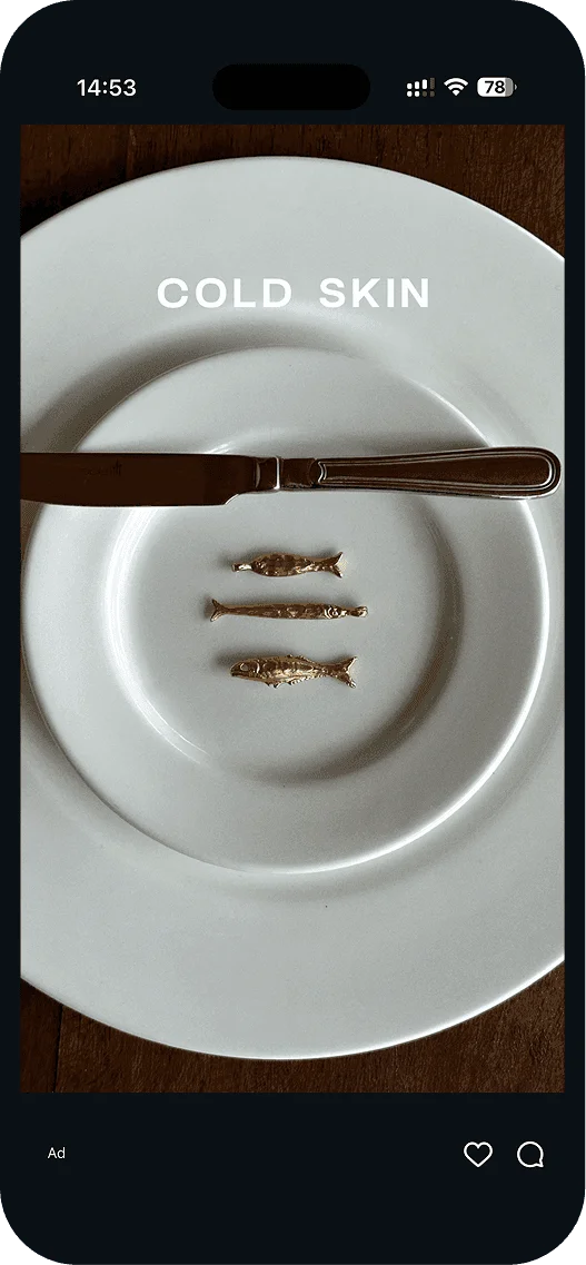 Cold Skin ad: gold fish charms on a white plate with a knife