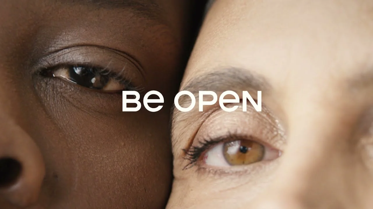 Still from the BE OPEN manifesto: two faces close together with the BE OPEN logo.