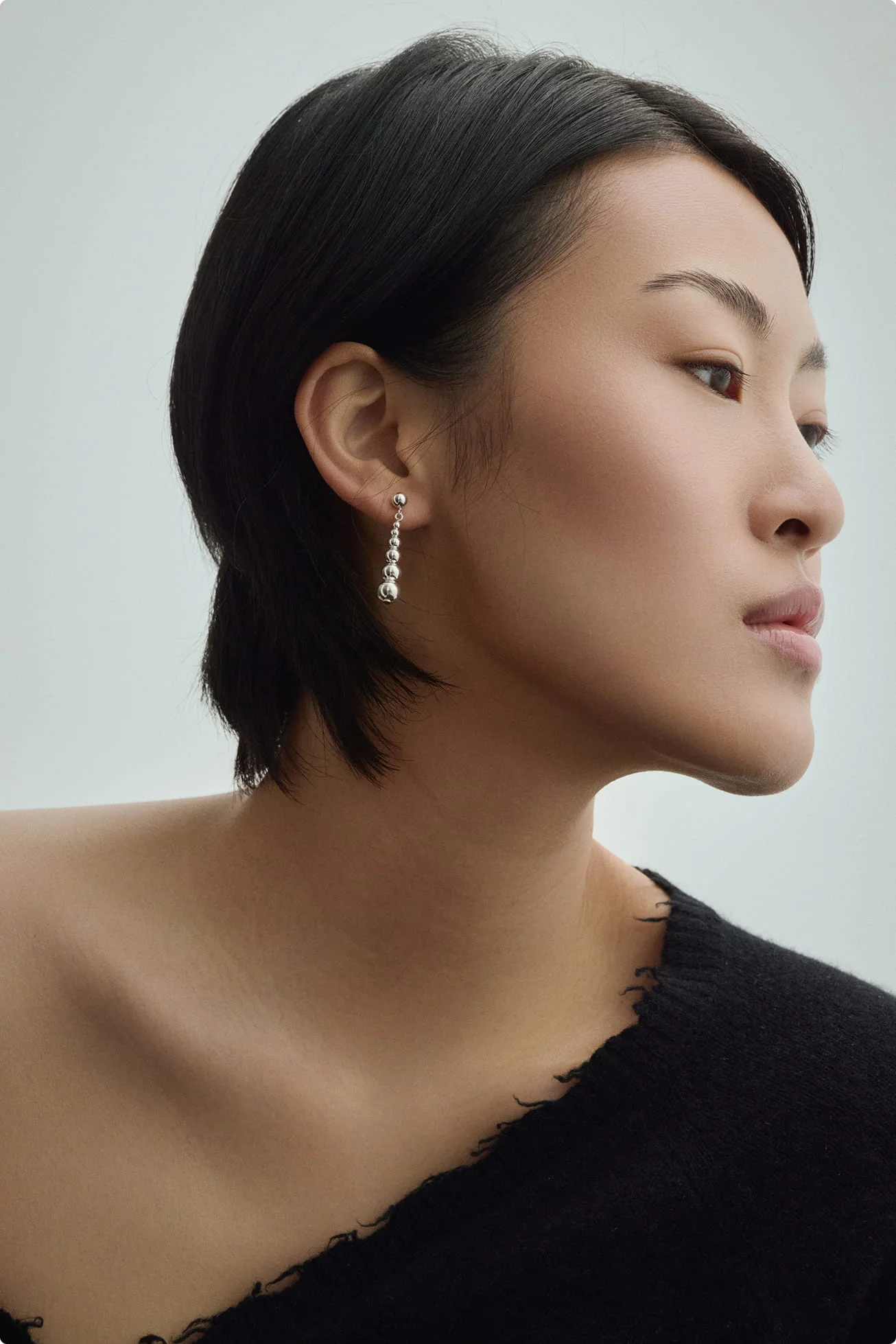 Woman in a black off-shoulder sweater wearing a silver drop earring