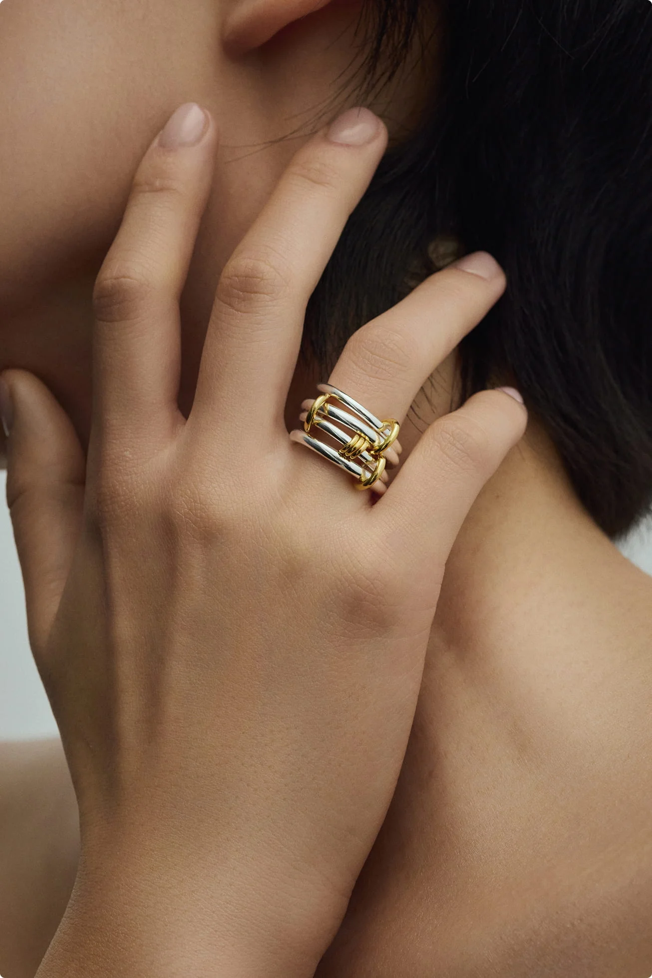 Hand with stacked silver and gold rings against bare skin