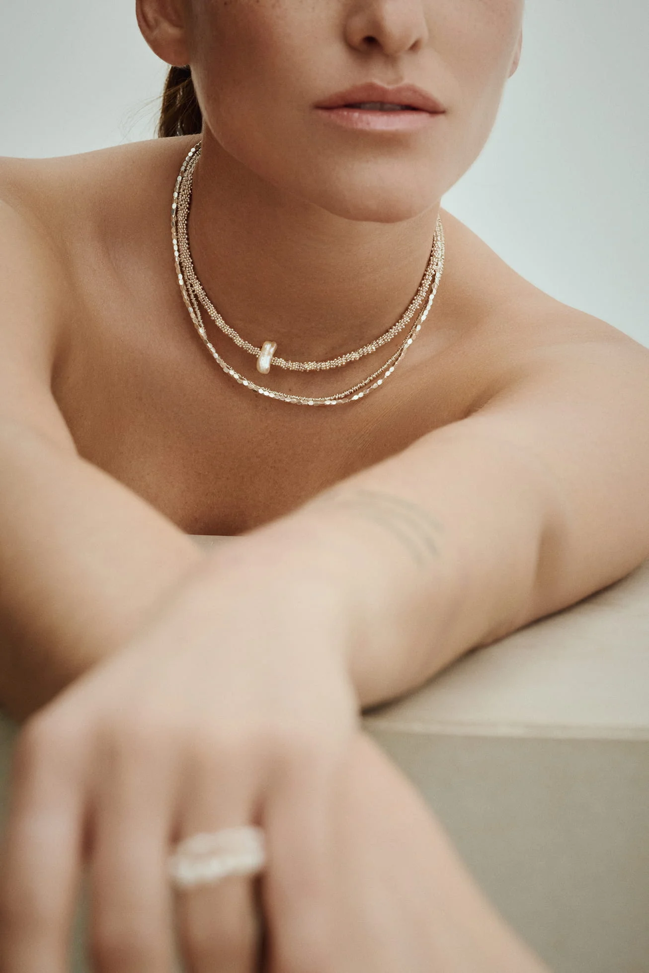 Woman wearing layered silver necklaces and a ring
