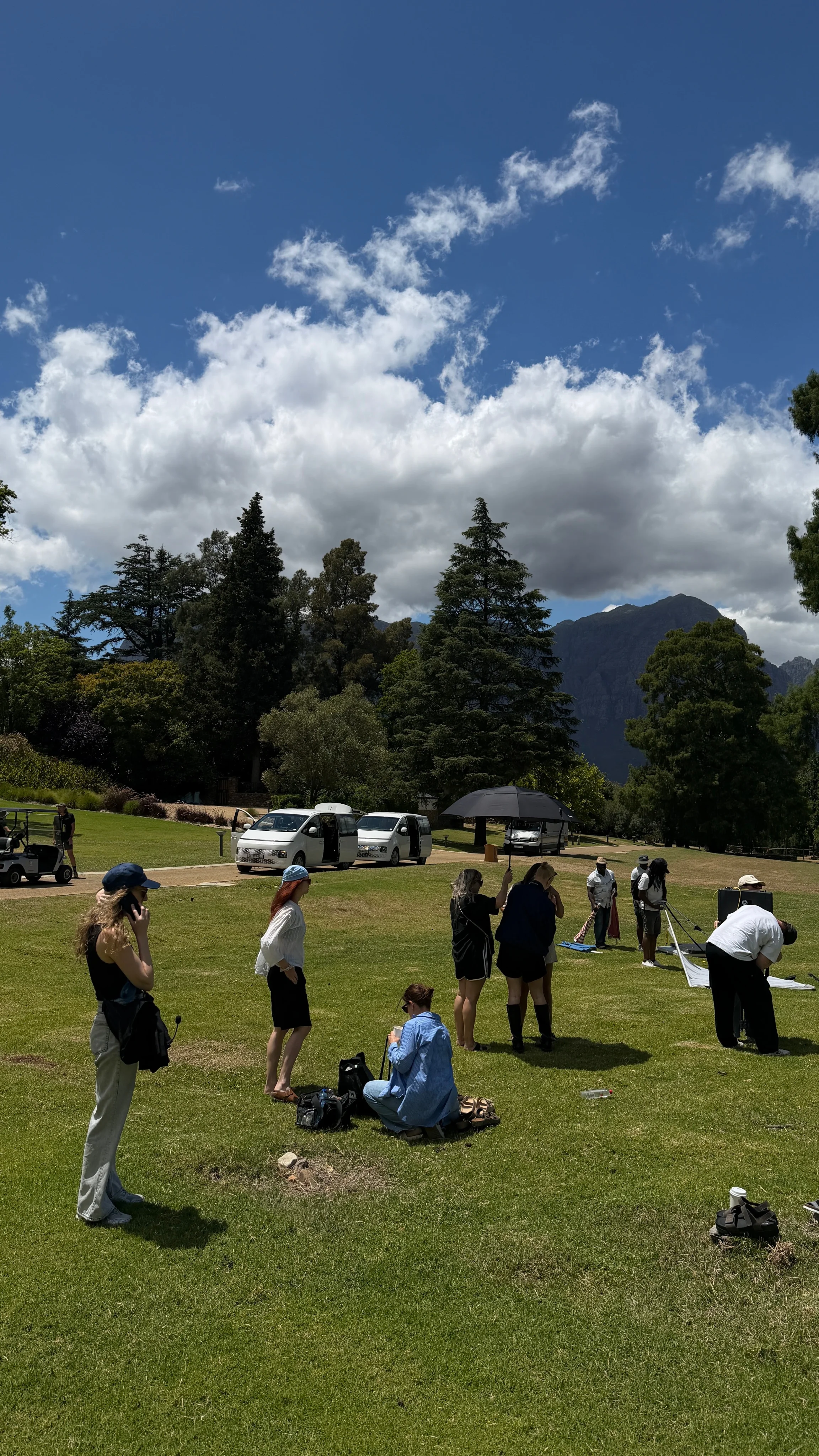 Crew and cars setting up an outdoor shoot on a meadow