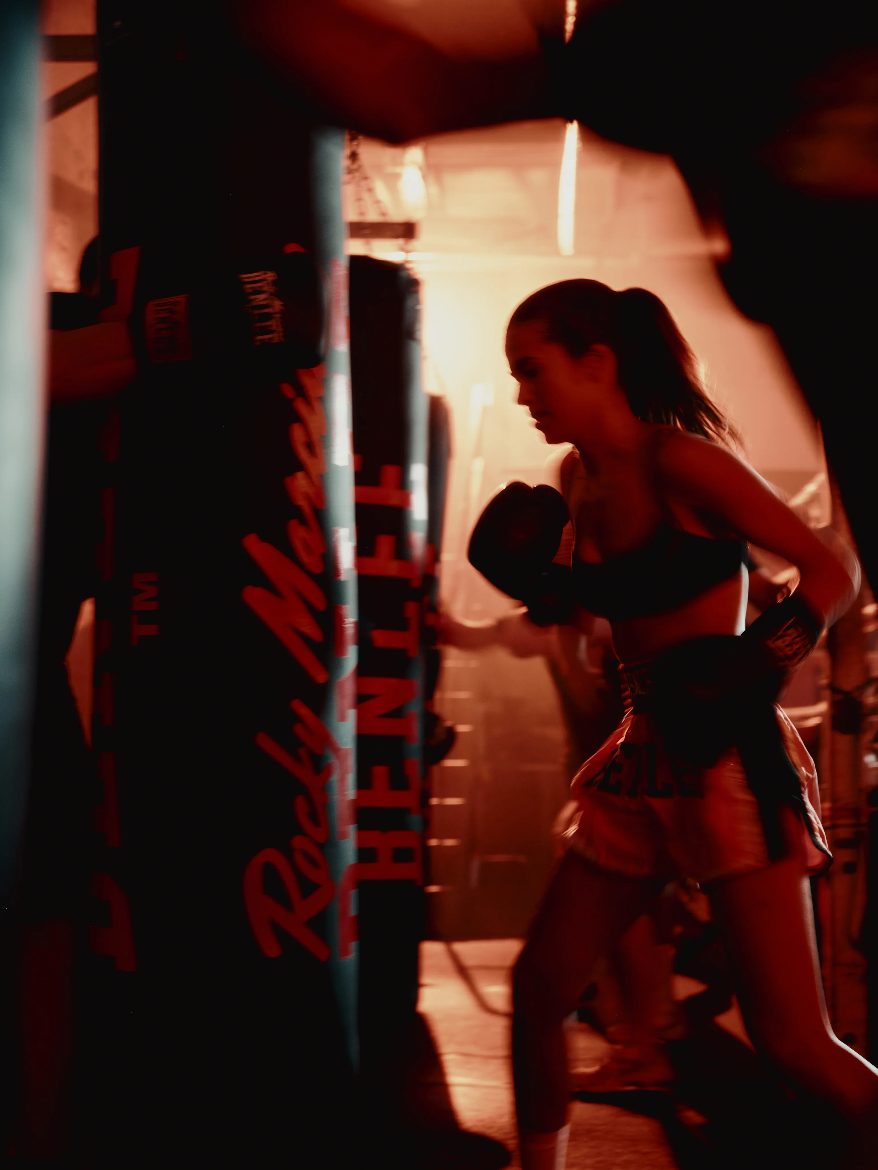 Boxer working a heavy bag in red light