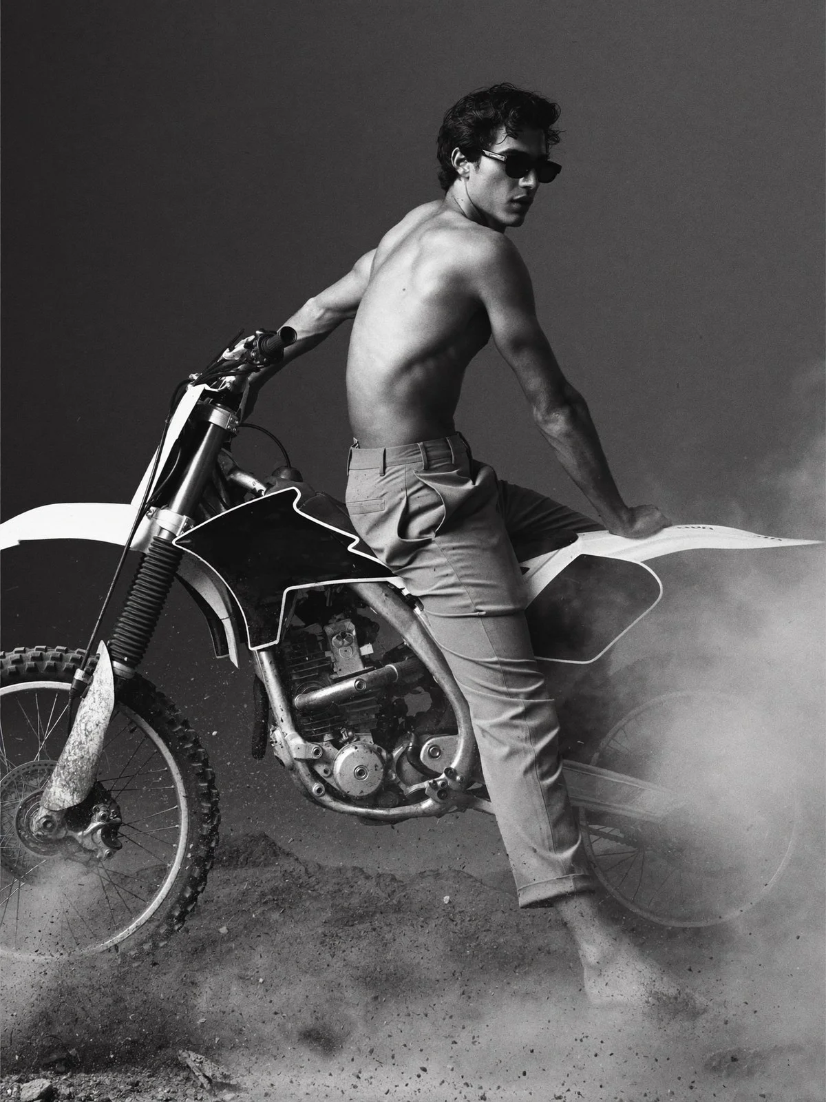 Black-and-white image of a shirtless man on a dirt bike
