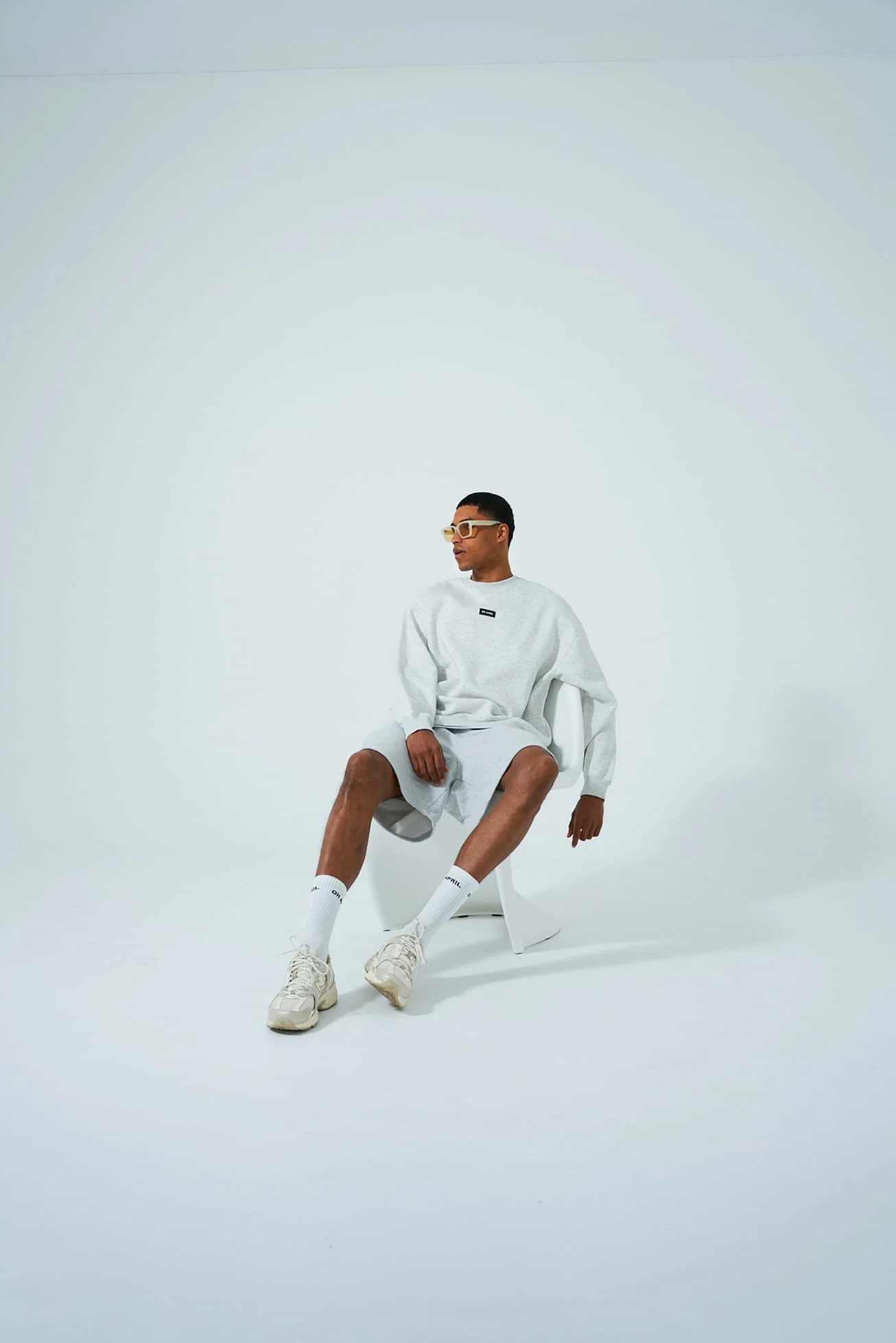 Model in light grey athleisure wear sitting in a white studio