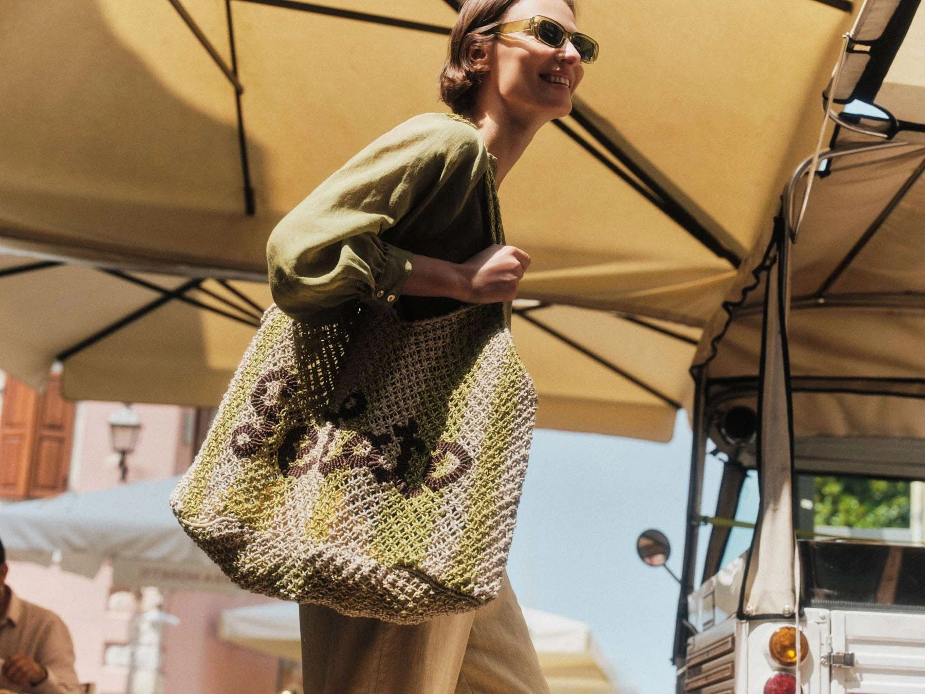 LANIUS campaign: model with a woven bag under a market awning