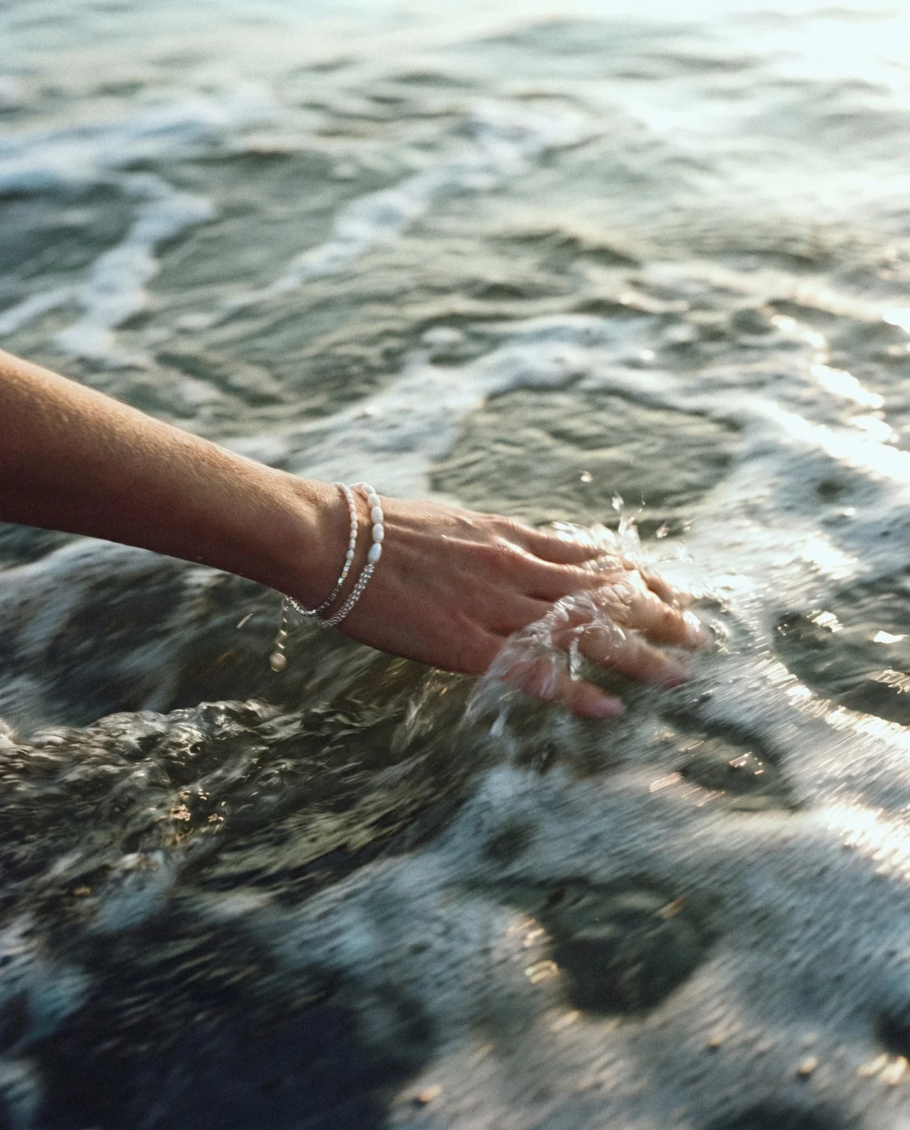 Hand with a pearl bracelet in sea water
