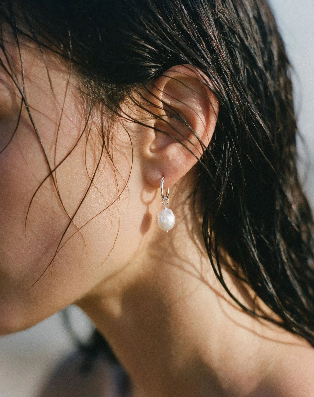 Close-up of a pearl earring and wet hair