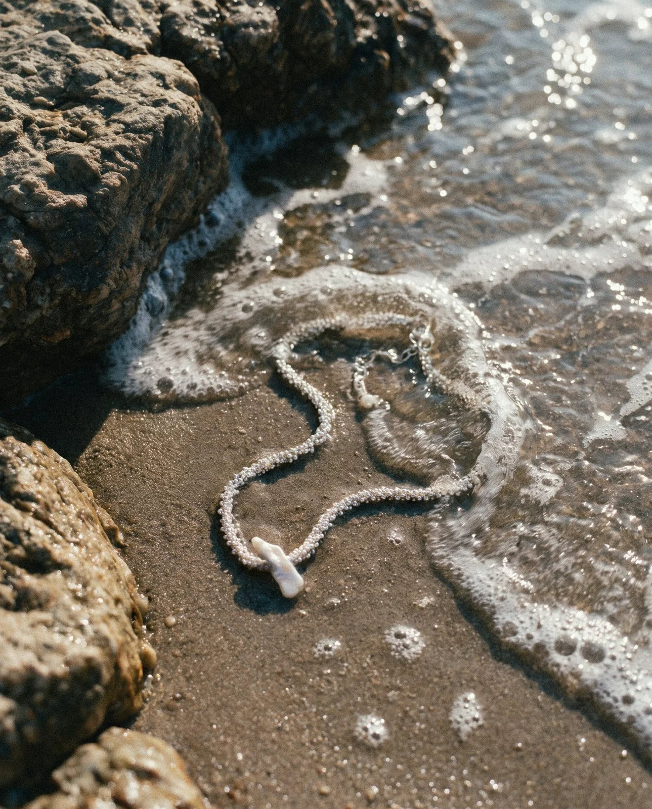 Pearl necklace on wet sand in the surf