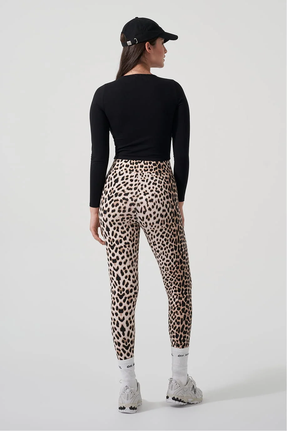 Model in a black top and leopard print leggings, back view
