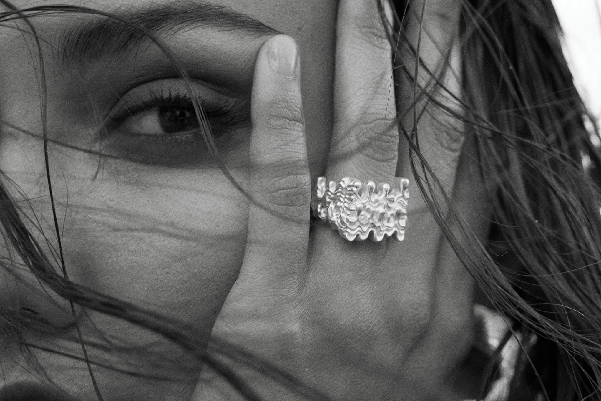 Close-up of eye and hand wearing a decorative ring