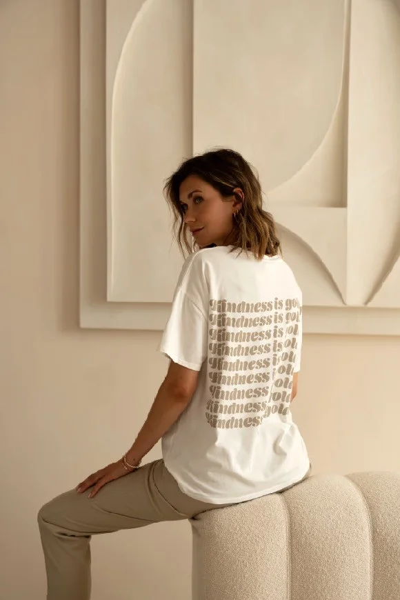 Woman in a white T-shirt with a stacked lettering print, seen from behind.