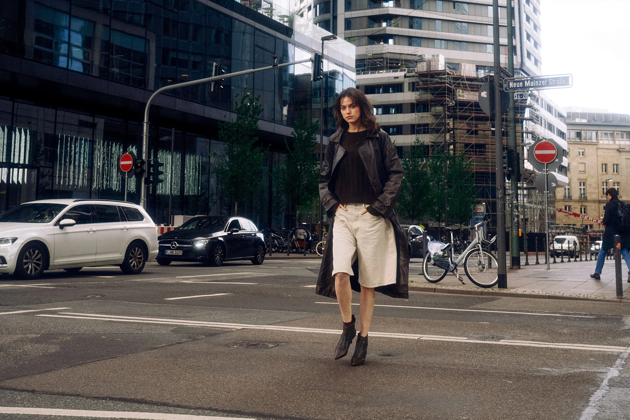 Woman walking in city street by traffic and buildings