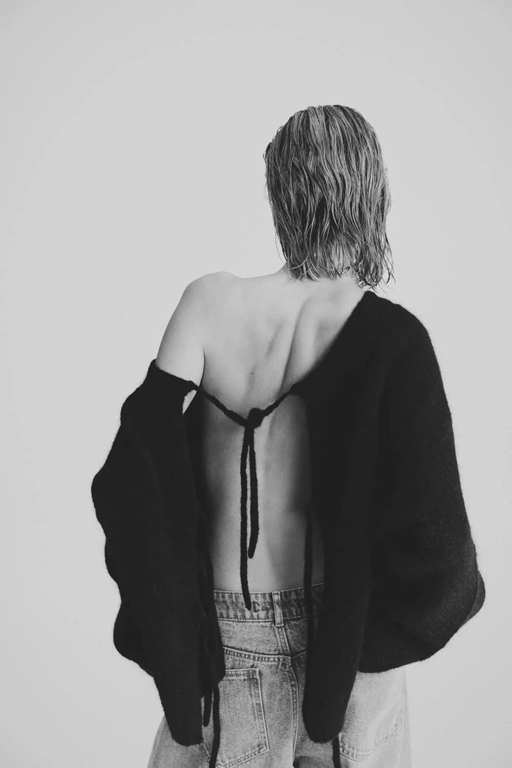 Model with back to camera, wearing a black knit top.