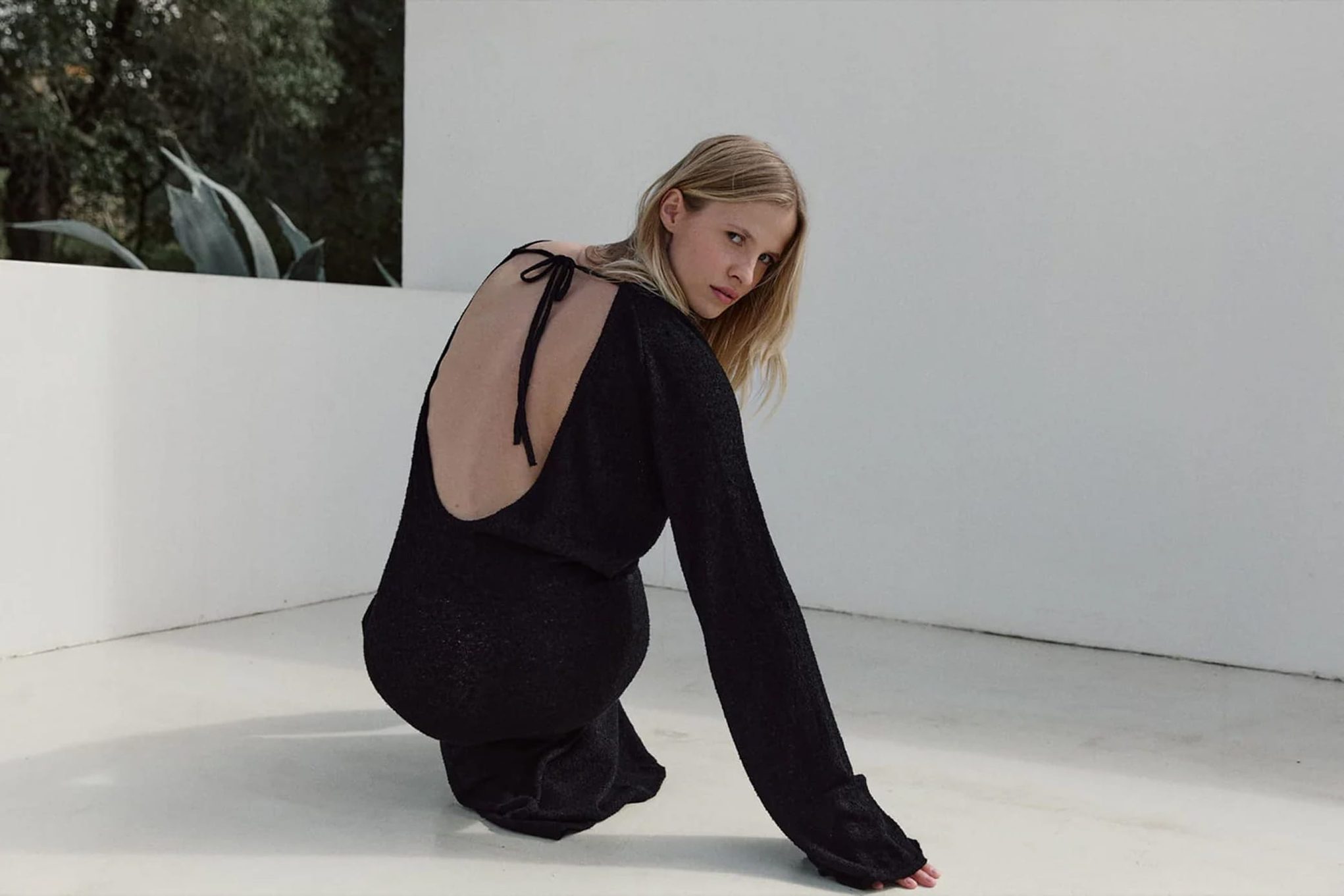 Model in black backless knit dress