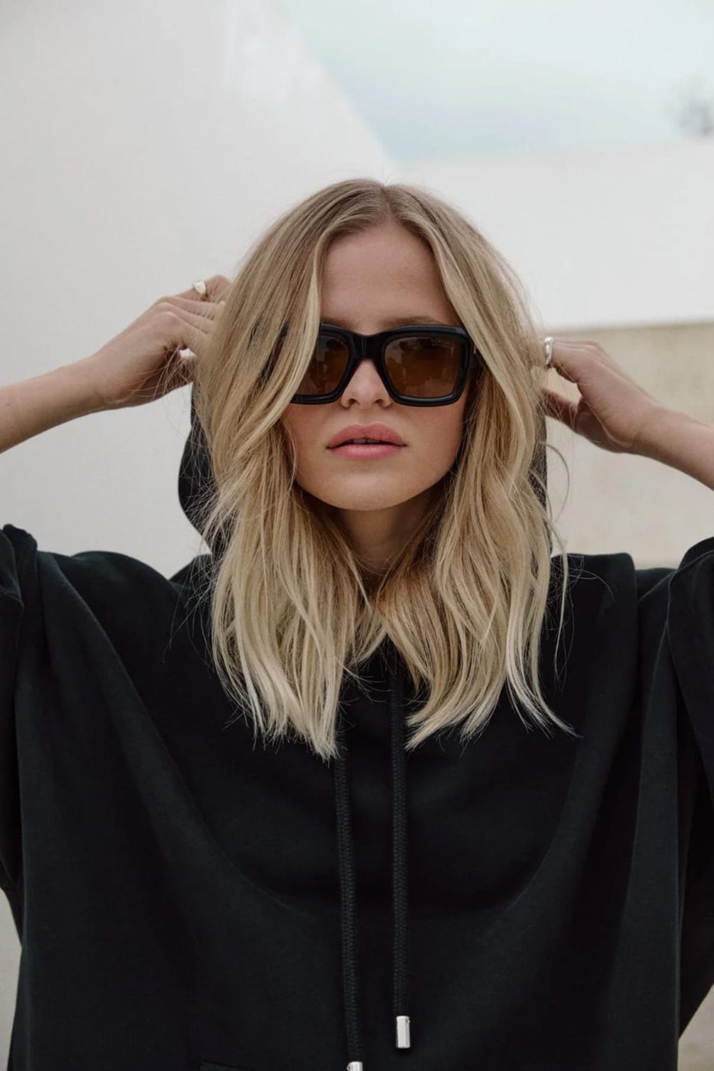 Model with sunglasses and hoodie.