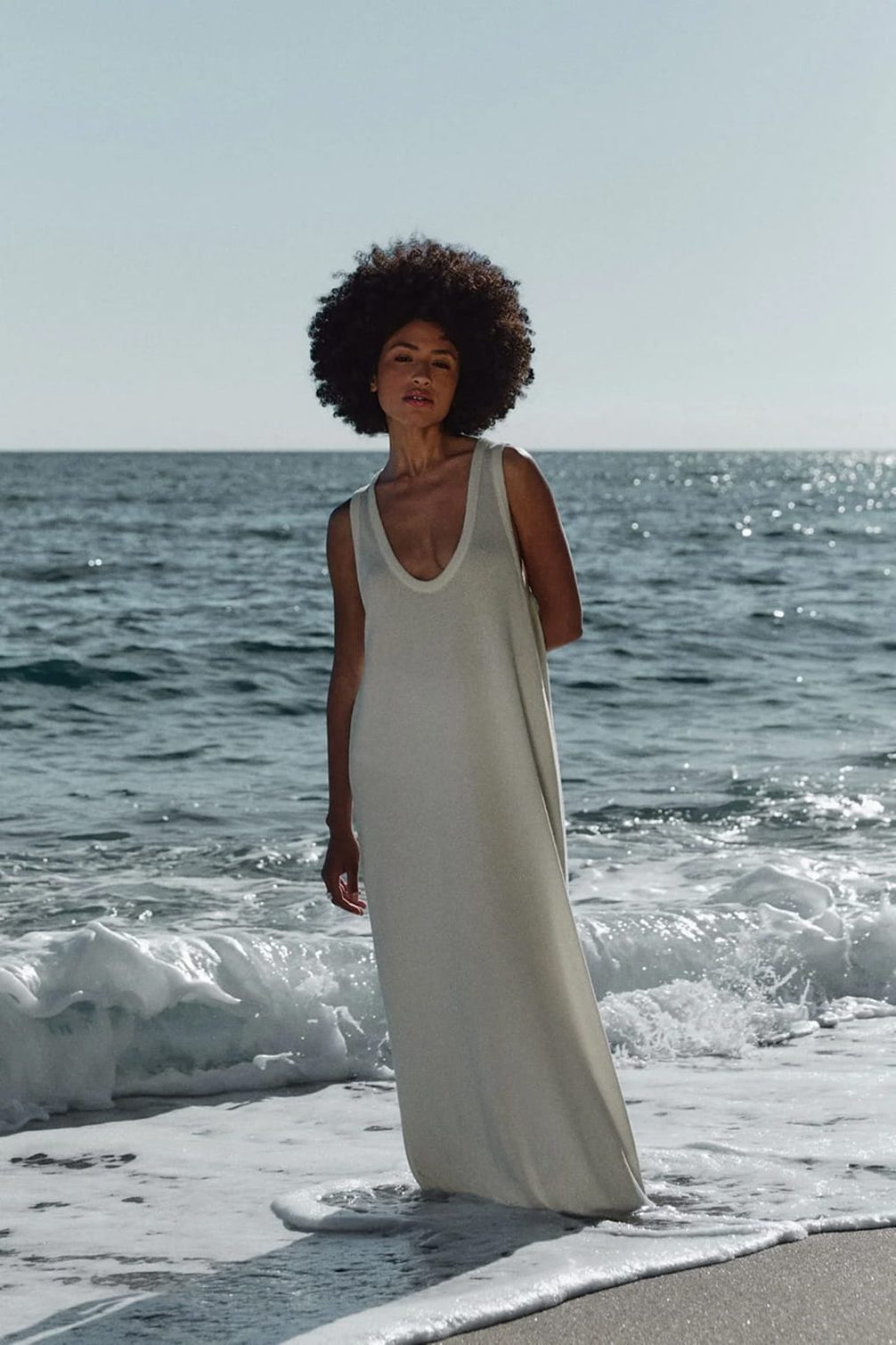 Woman in white dress on beach with ocean waves