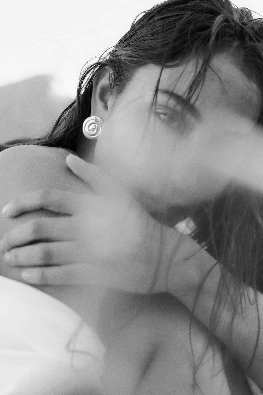 Woman with a swirled earring and hand on shoulder