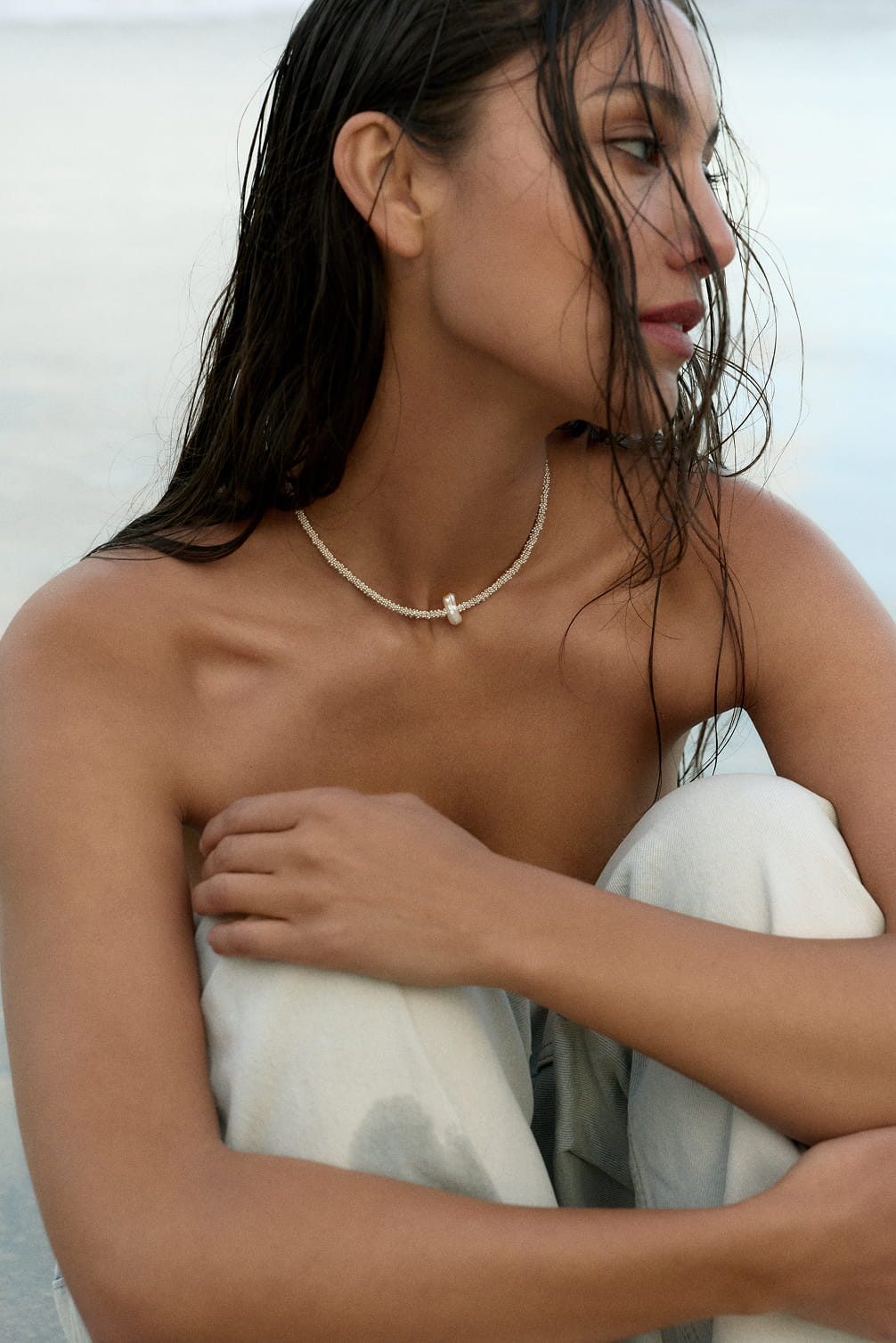 Woman with wet hair and pearl necklace on beach