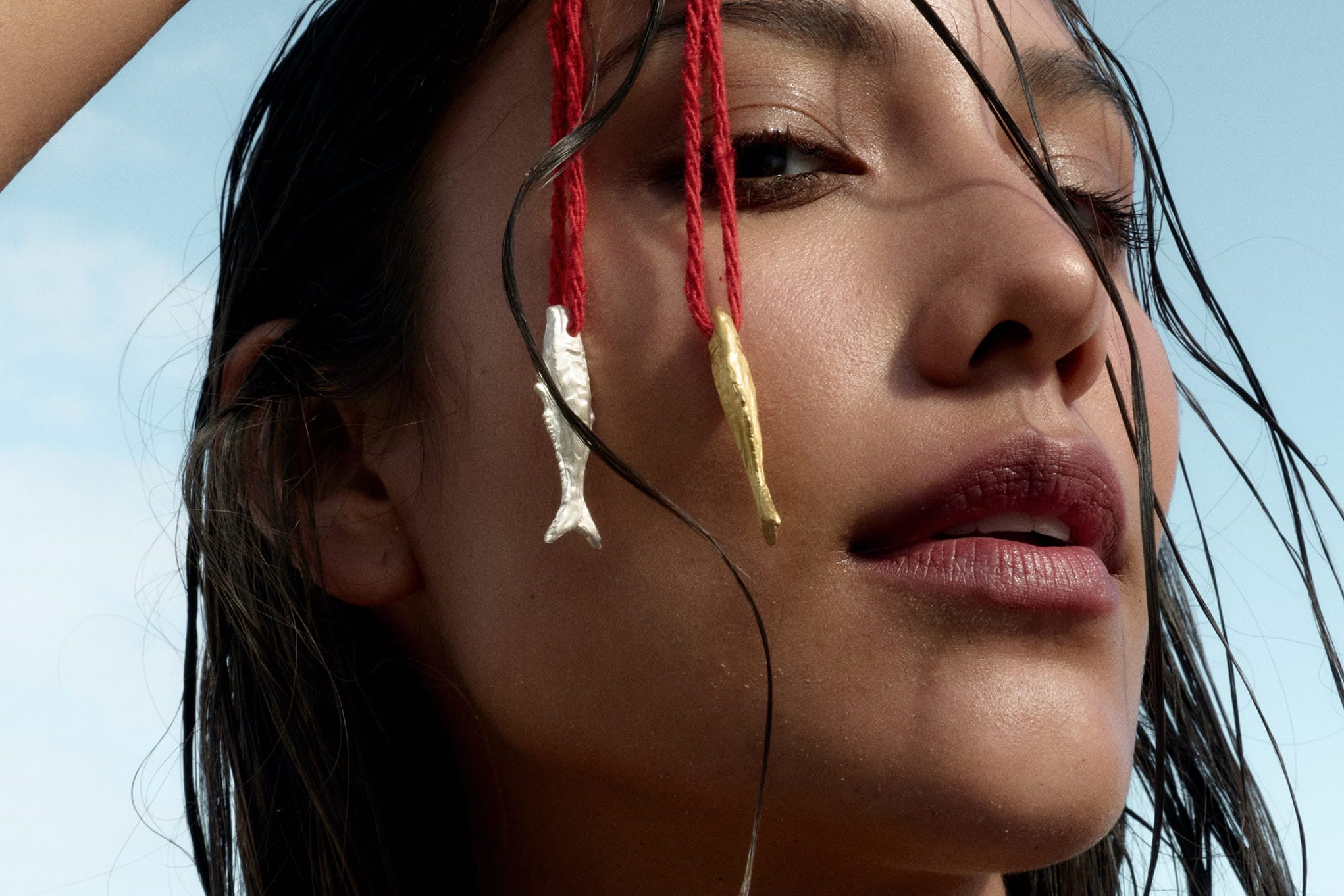 Model with two fish pendants on red string earrings