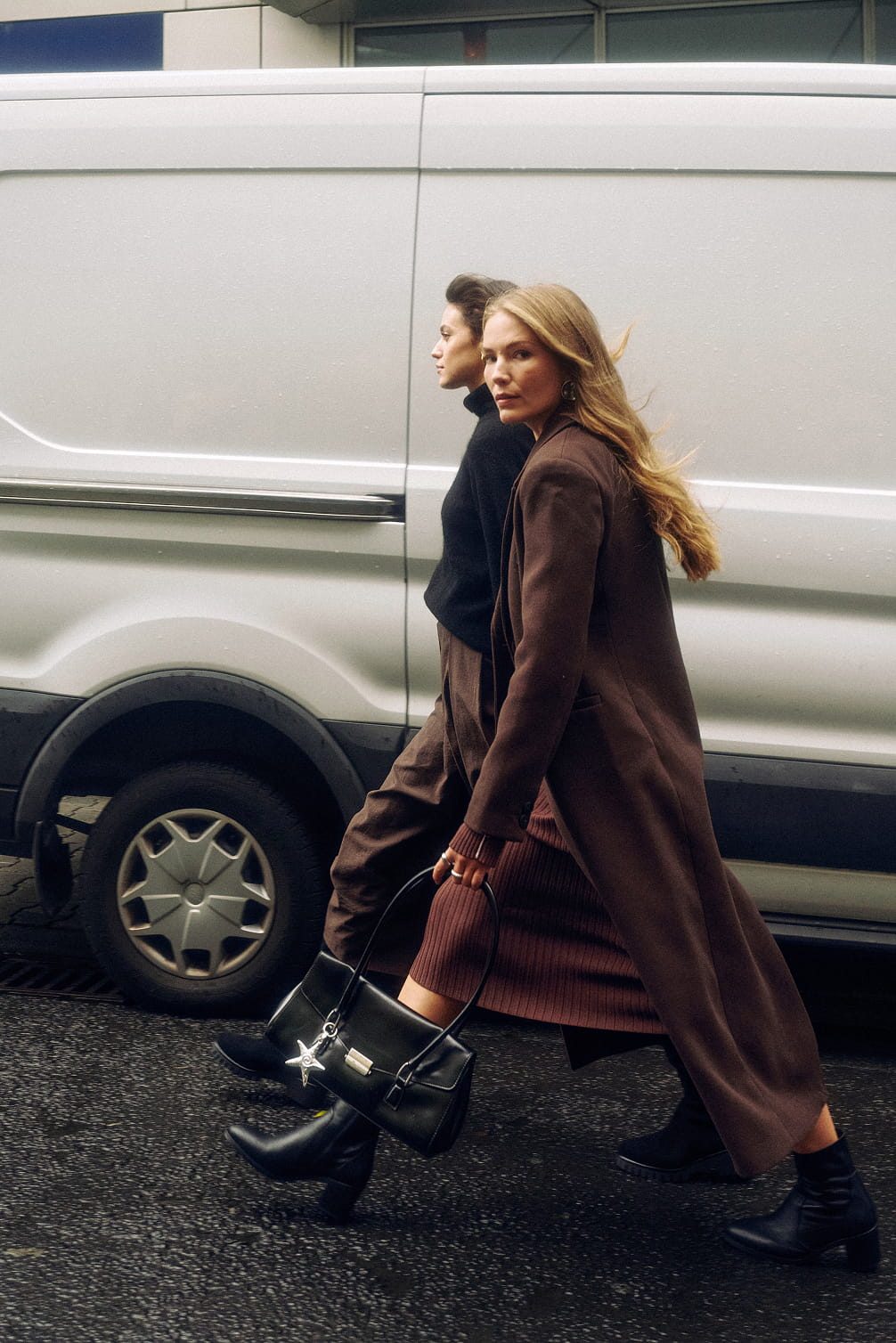 Two women walk past a white van.