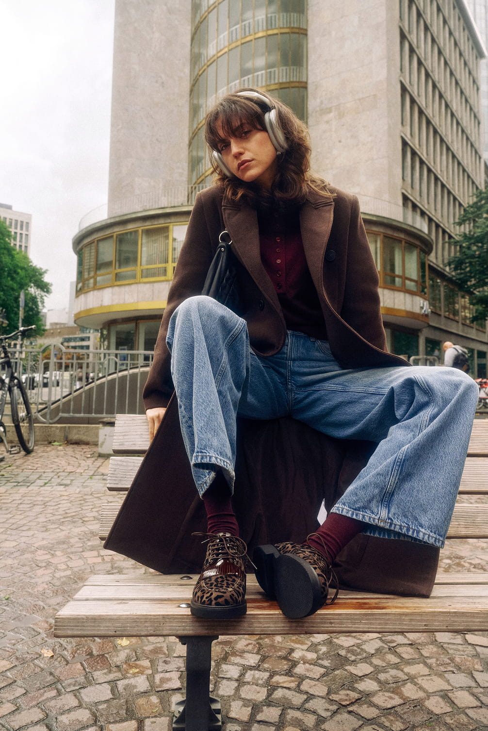 Woman with headphones and leopard shoes on bench.