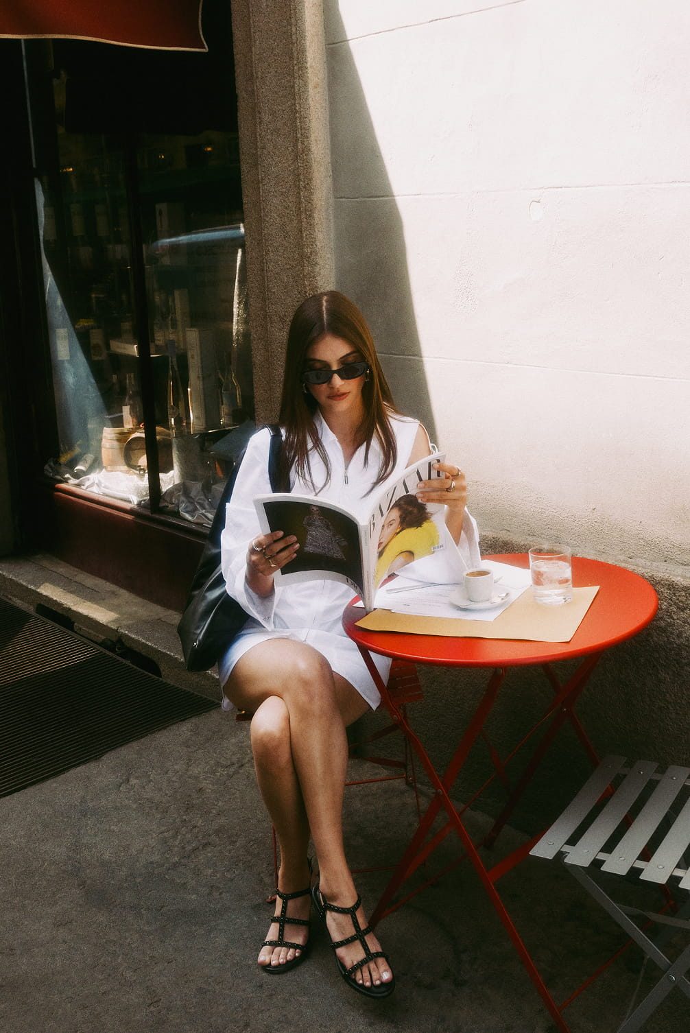 Woman reading magazine at cafe table.