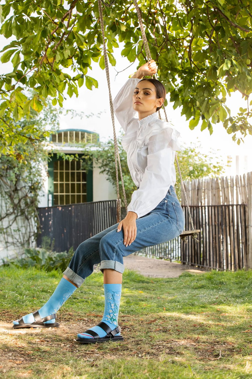 Model on swing in blue jeans and patterned socks.