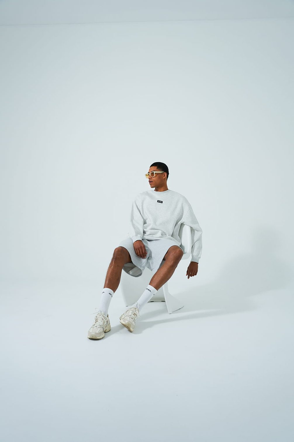 Model in light grey athleisure wear and yellow sunglasses.