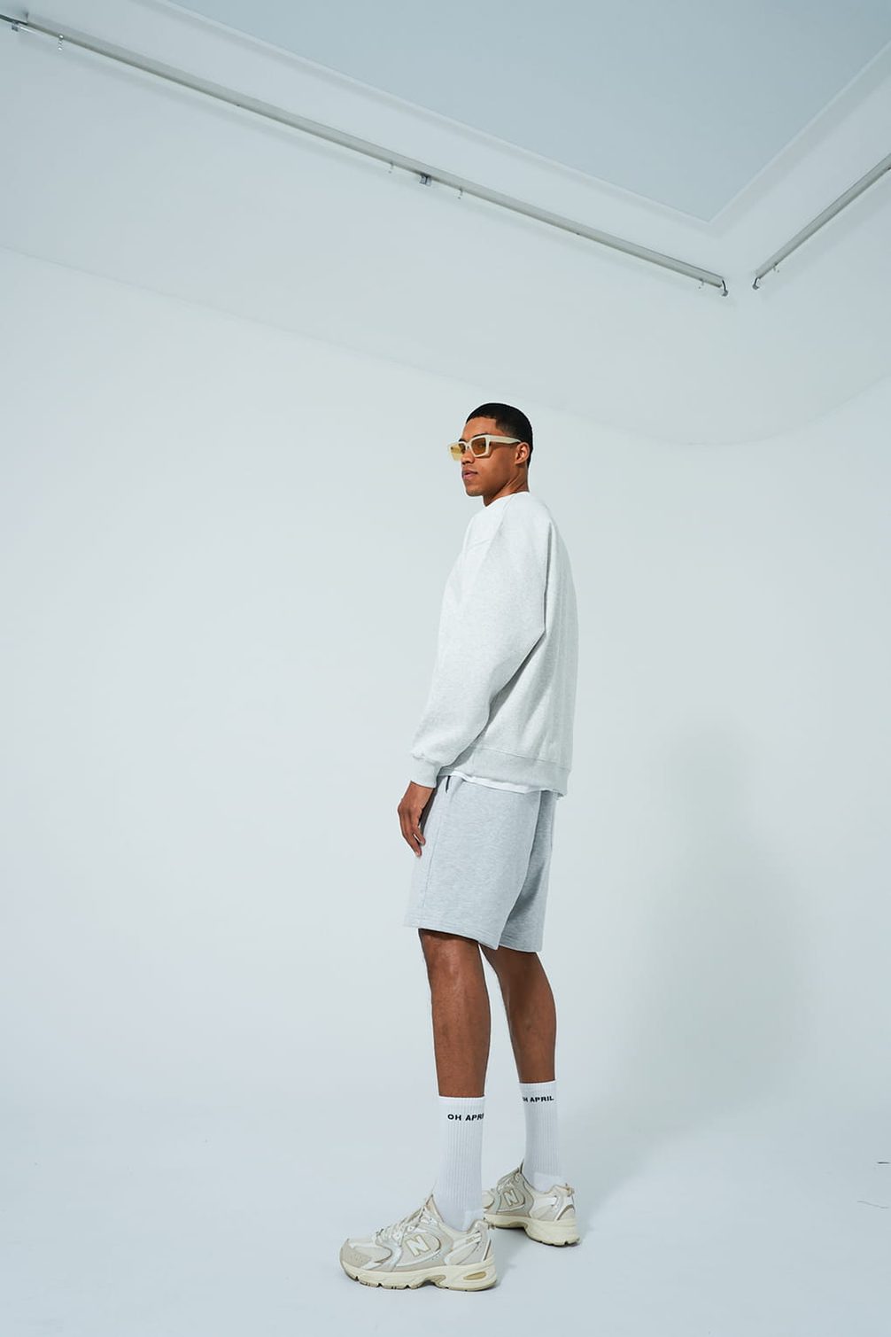 Model in grey loungewear and sunglasses.