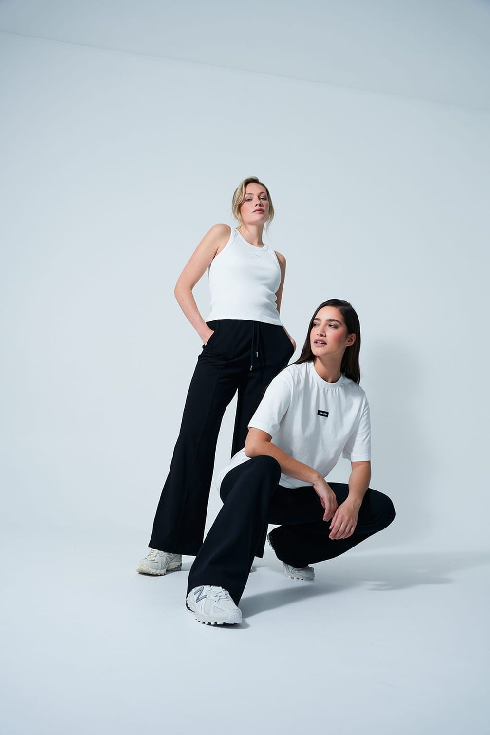 Two models in white tops and black trousers from the Oh April Essentials collection.