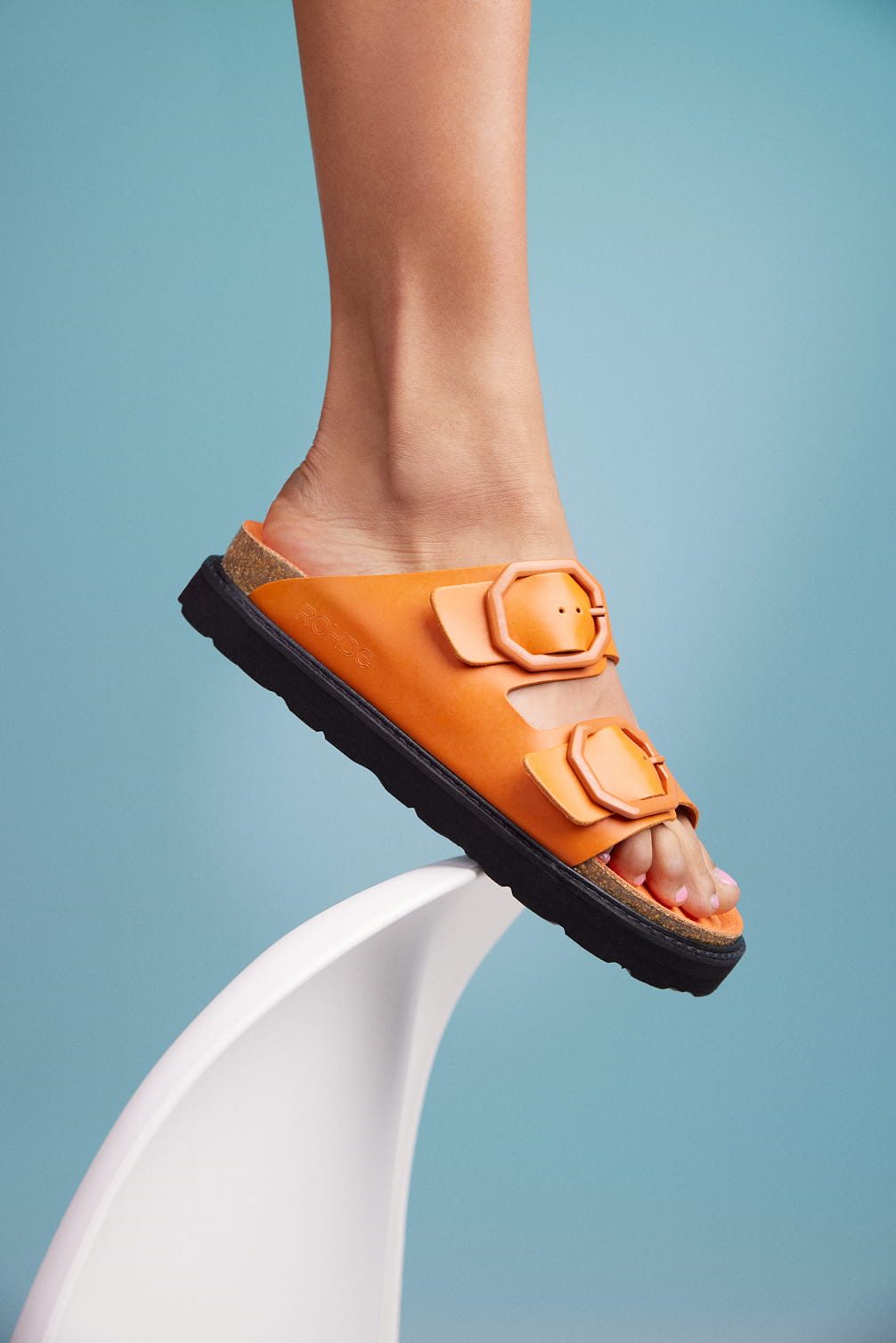 Rohde orange buckle sandals on white display.
