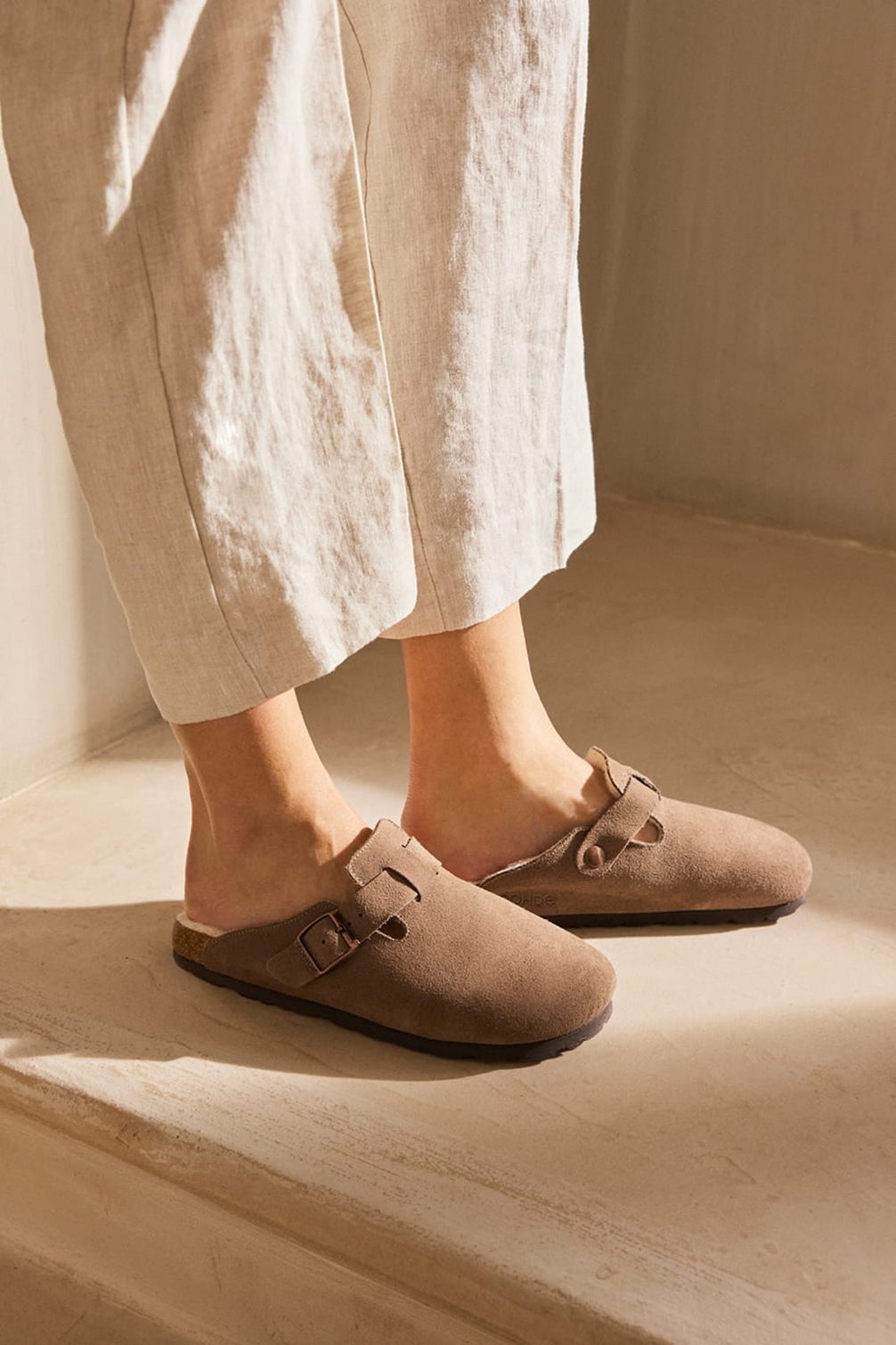 Brown suede clogs with buckles.