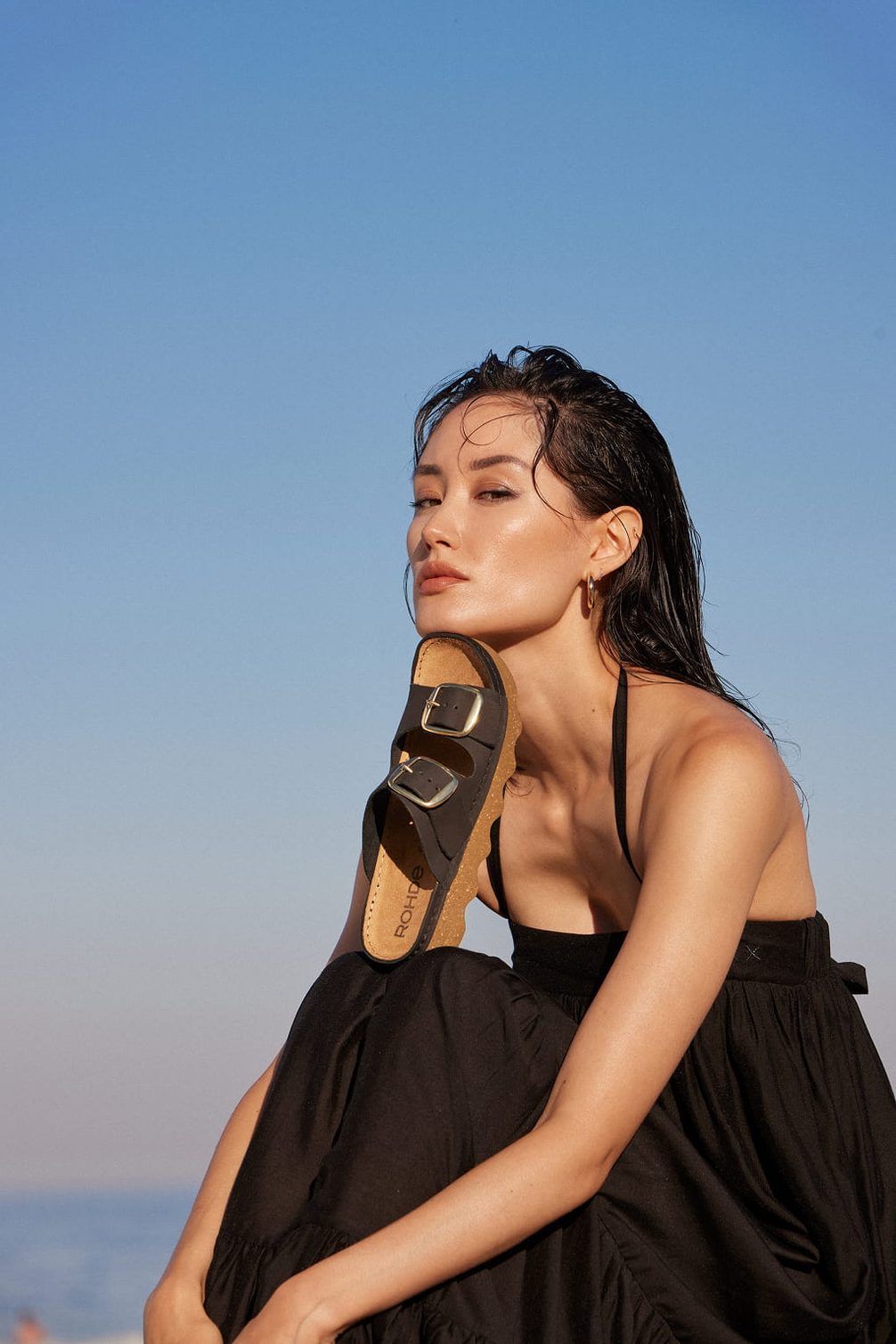 Woman holding black sandal with gold buckles