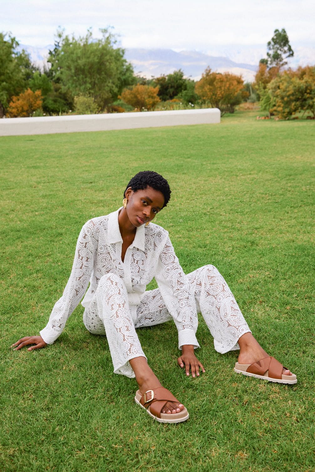 Model in white lace set on grass with mountains background