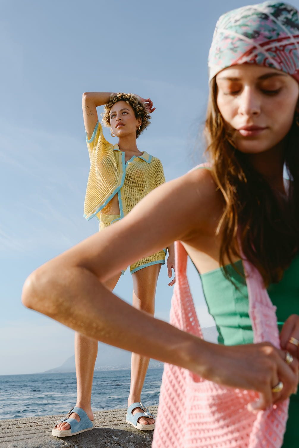 Two women by the sea in summery attire.