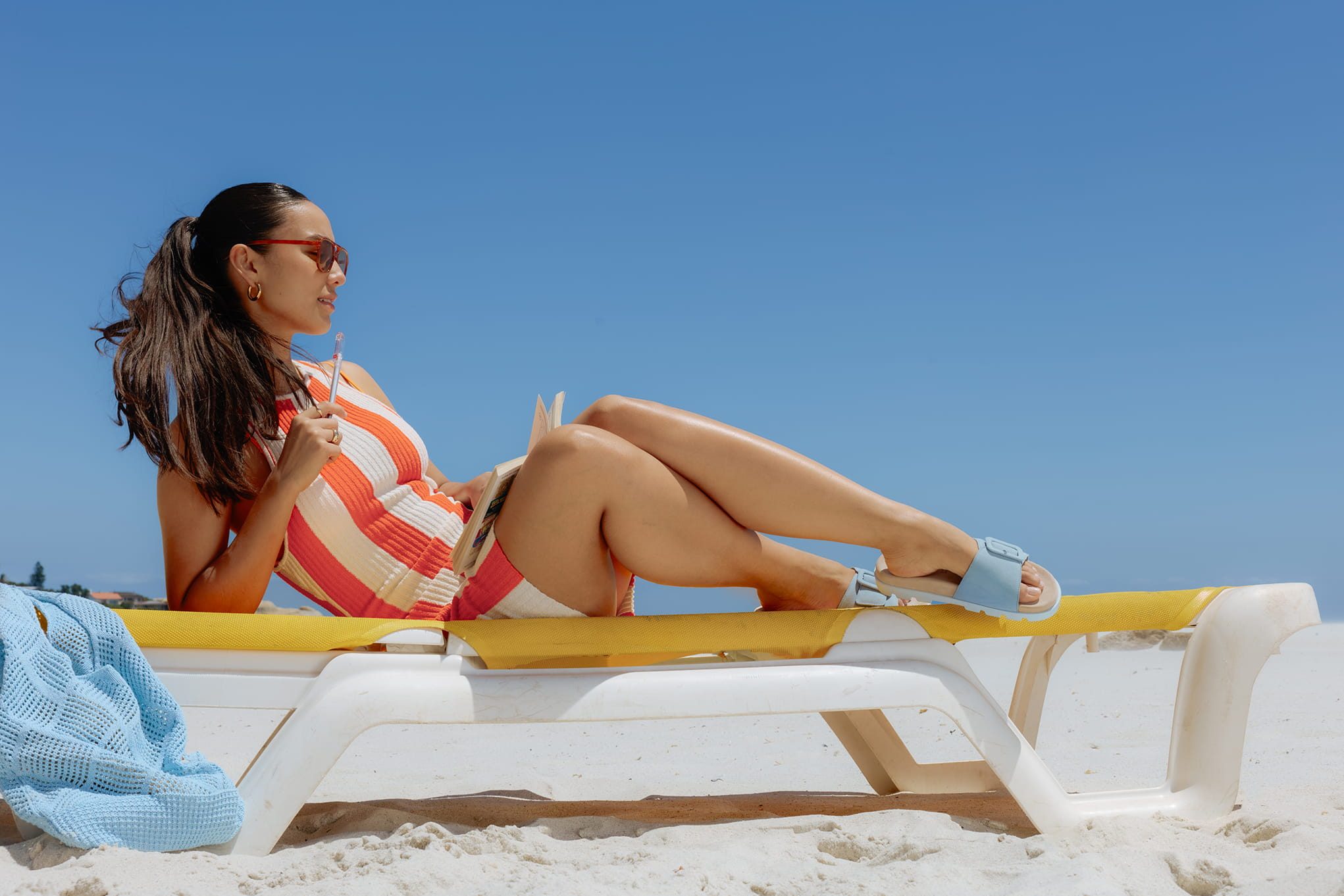 Woman reading on a lounge chair at the beach