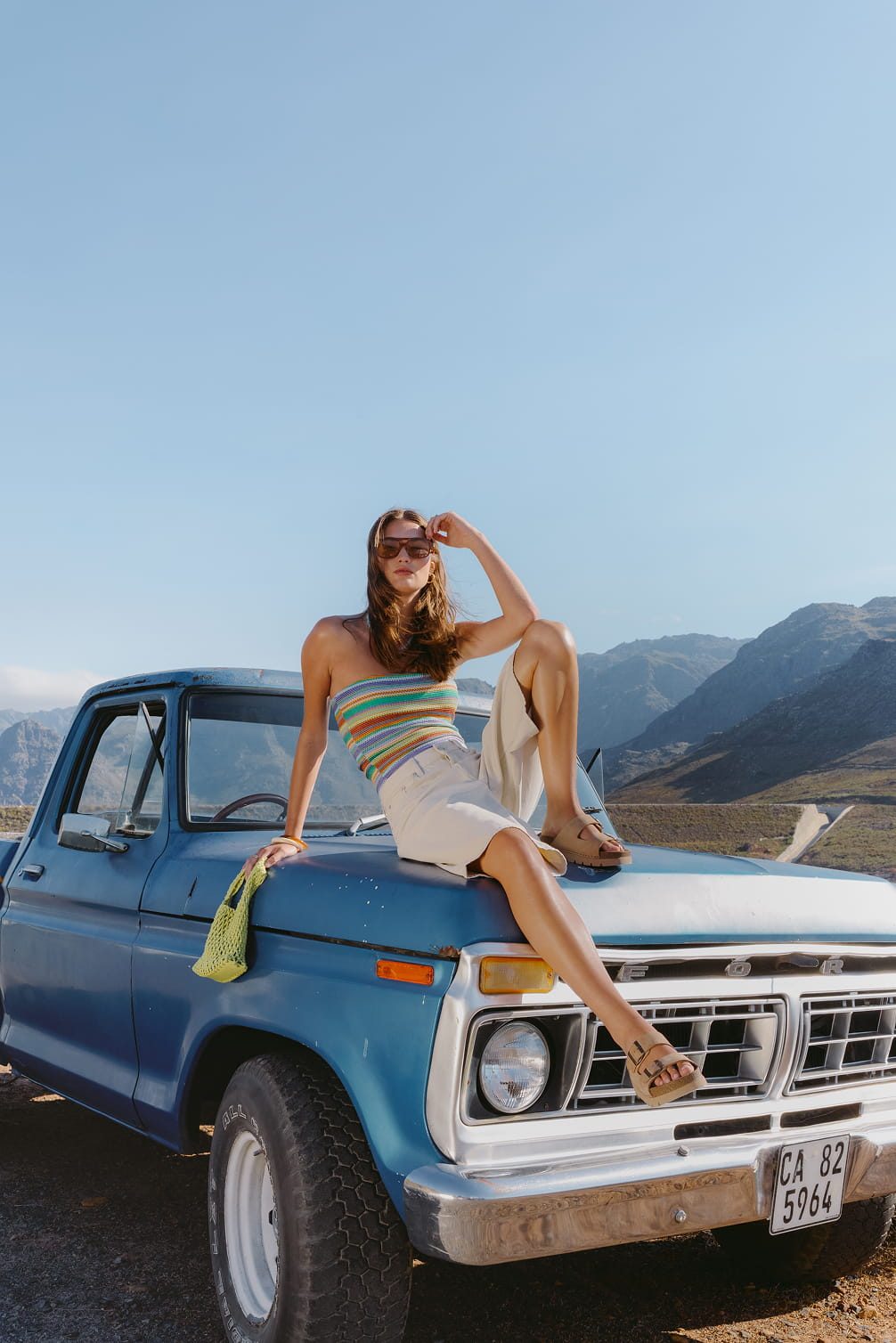 Woman in stripe halter top and white shorts on blue truck