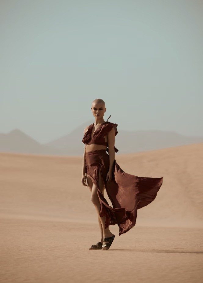 Woman with shaved head in flowing desert attire