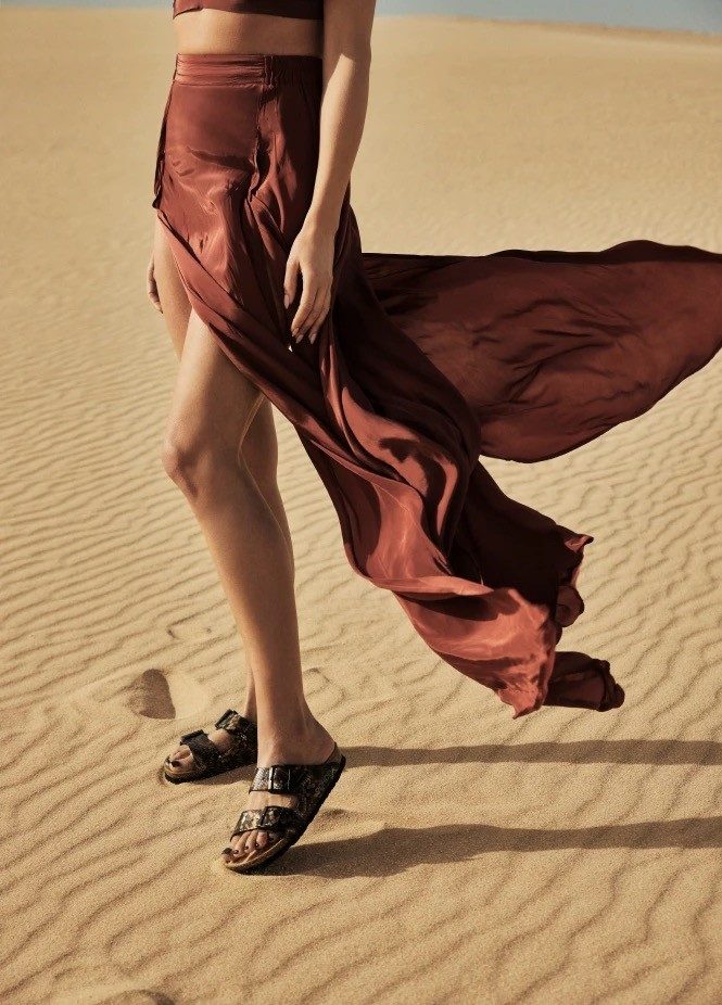 Woman walking in sand with flowing skirt
