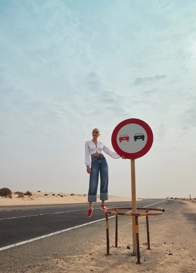 Woman next to a no-overtaking sign in a desert landscape