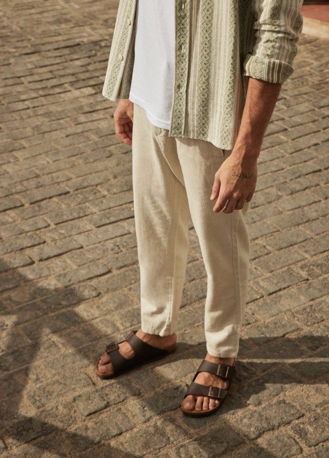 Man in linen pants, patterned shirt, and sandals